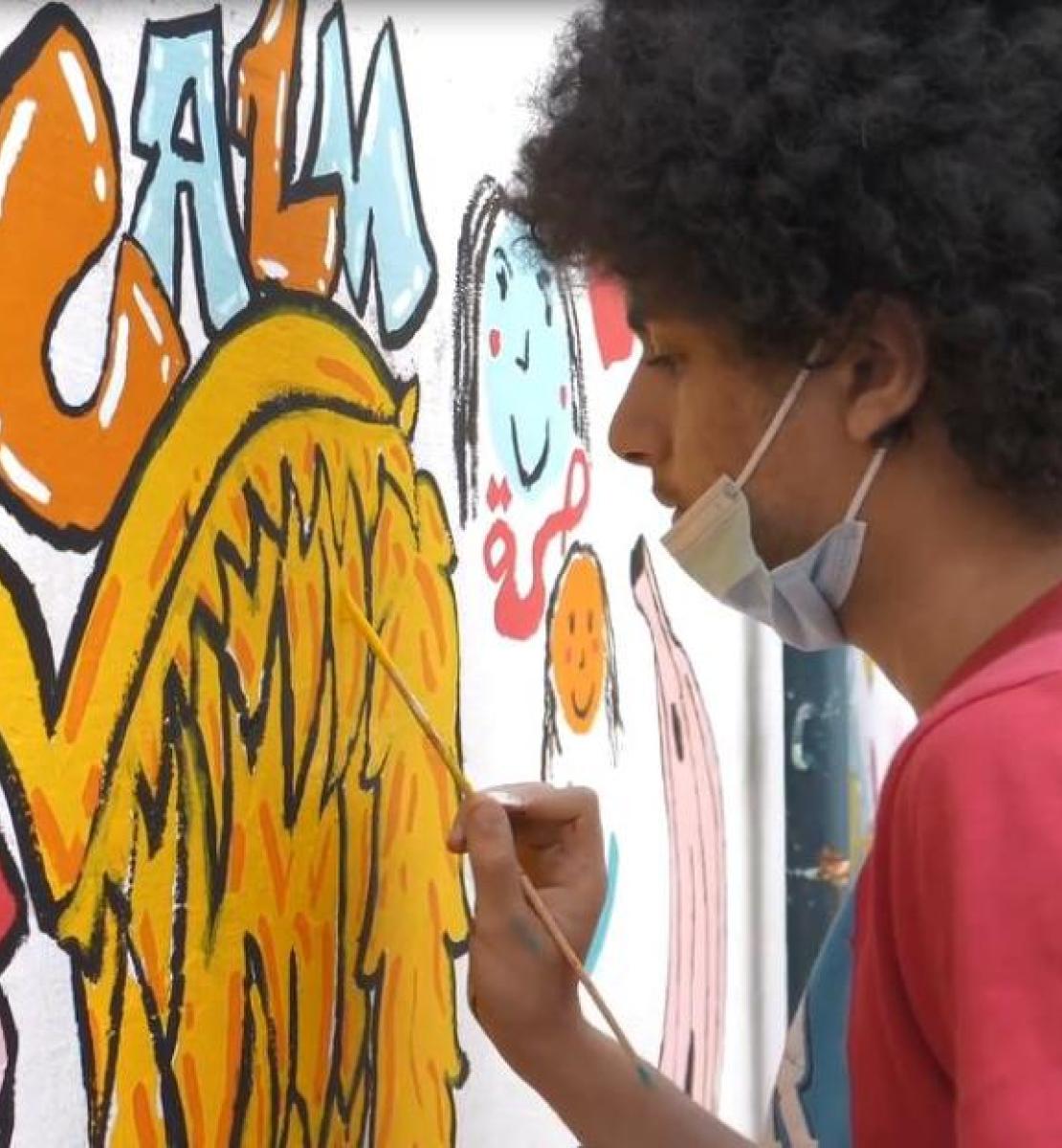 Child painting a mural in the playground of Khaled Bin Waleed School in Beirut, which was damaged by the port blasts and rehabilitated by UNESCO