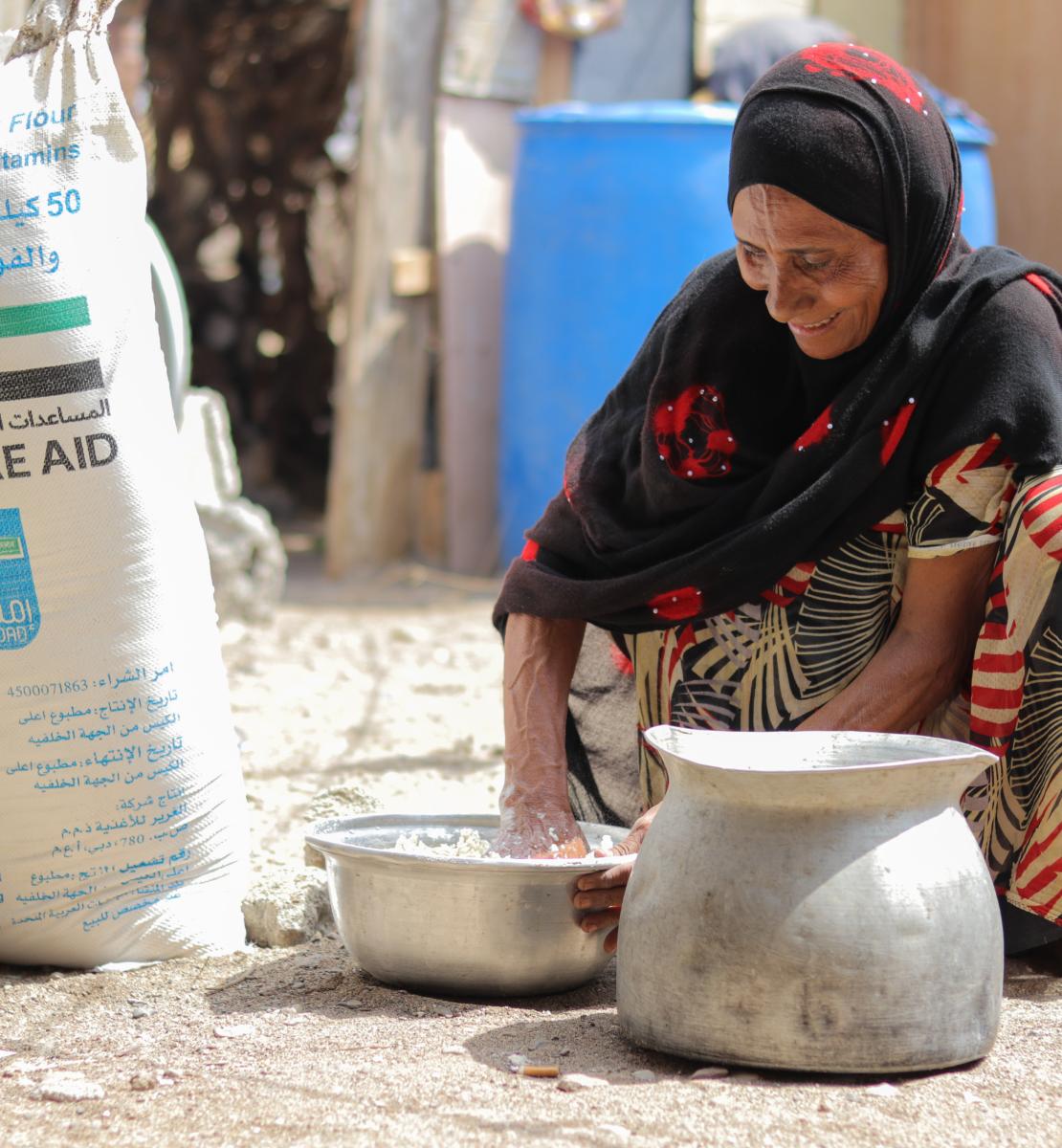 一名妇女用世界粮食计划署每月发放给她的面粉制作面包，这是粮食计划署发放给她的部分粮食配给。