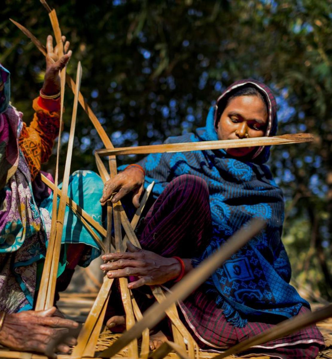 Women in colorful scarves work with wood in Bangladesh.