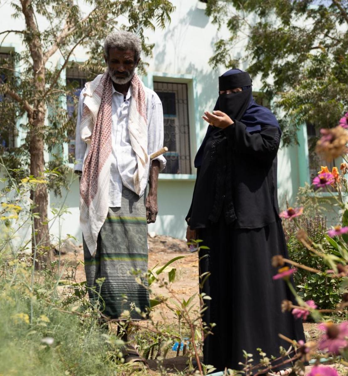 A man and a woman wearing a veil in a small garden.