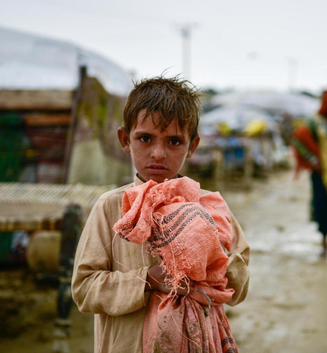 巴基斯坦俾路支省发生洪灾。一个孩子拿着自己的财物，当地人正纷纷搬到了更安全的地区。