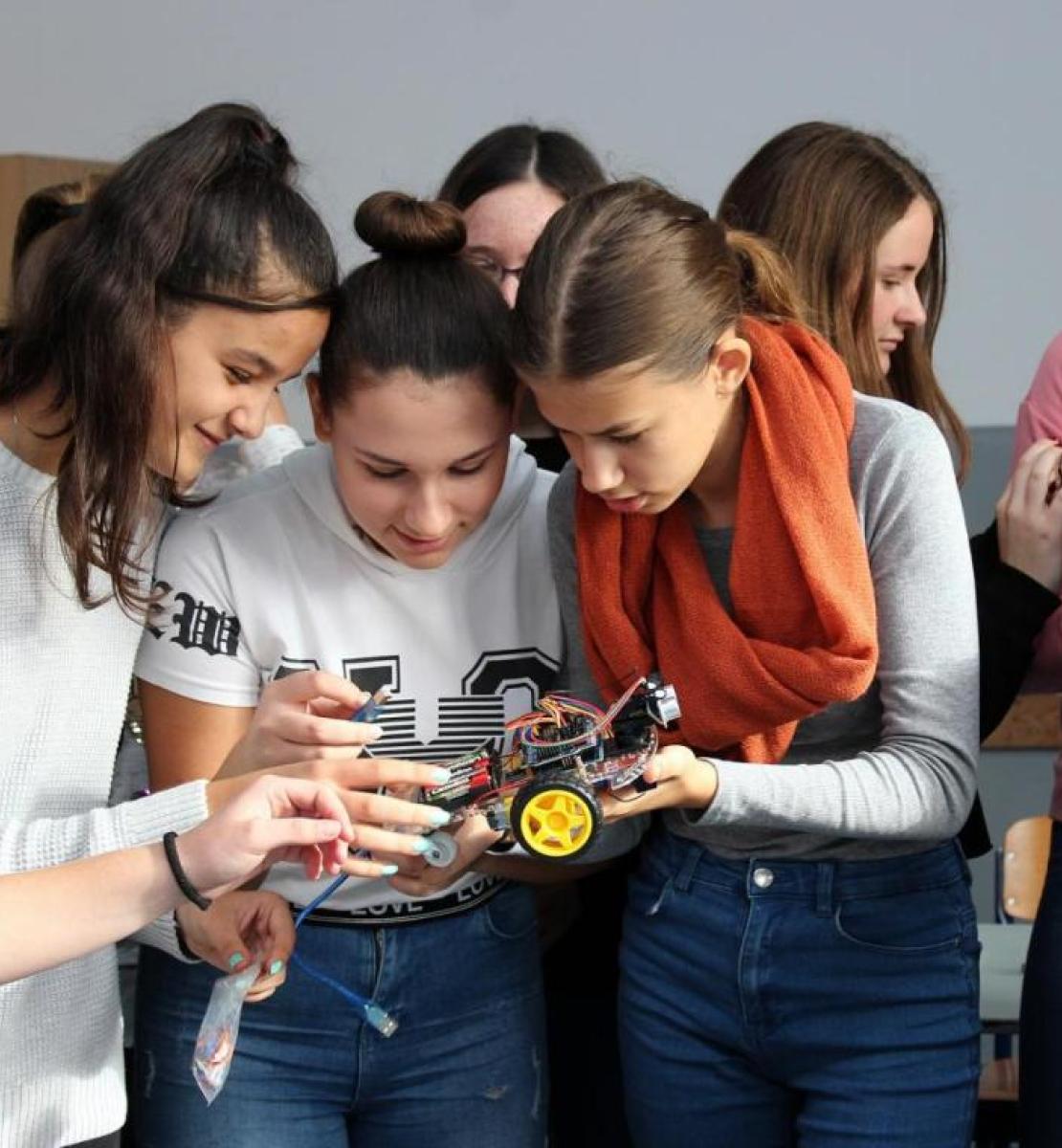 A group of school girls working on a robot car model. 