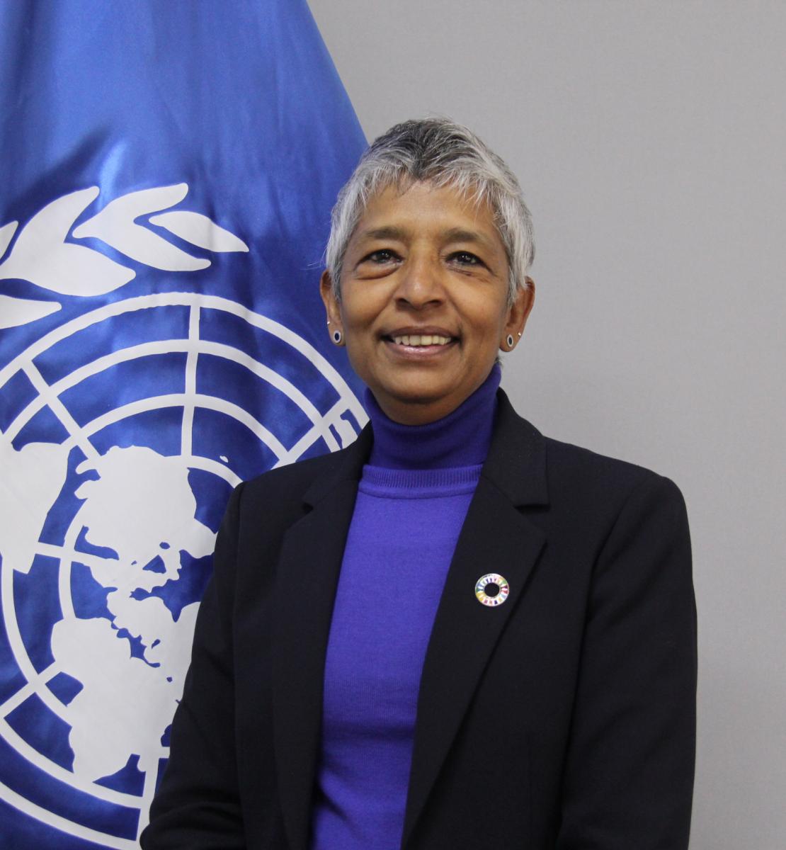 Woman in a suit in front of a UN flag
