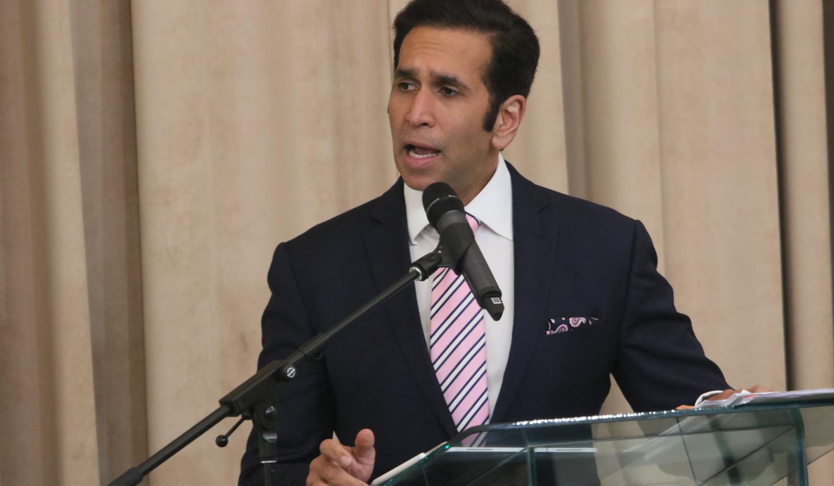 Faris Al-Rawi, Attorney General of Trinidad and Tobago shown speaking into a microphone at a podium on stage.