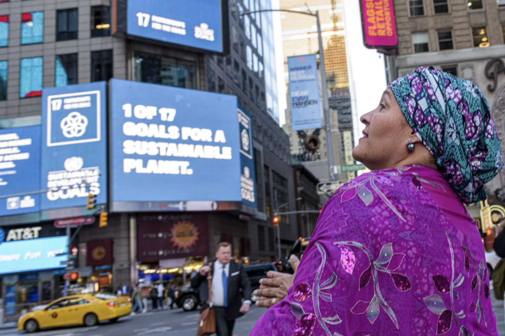 Amina Mohammed, Vicesecretaria General de la ONU, mira de reojo a la cámara mientras observa la proyección de uno de los ODS en tres de las pantallas de Times Square, en Nueva York.