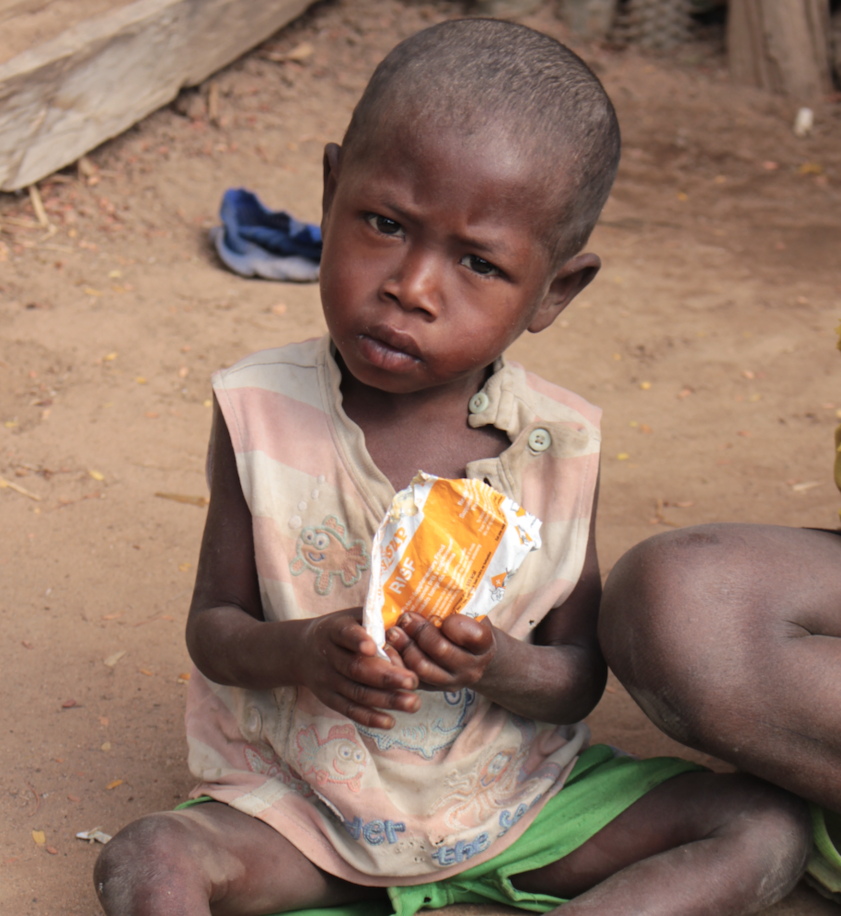 A young child in a pink and white shirt holds a food supplement in their hands.