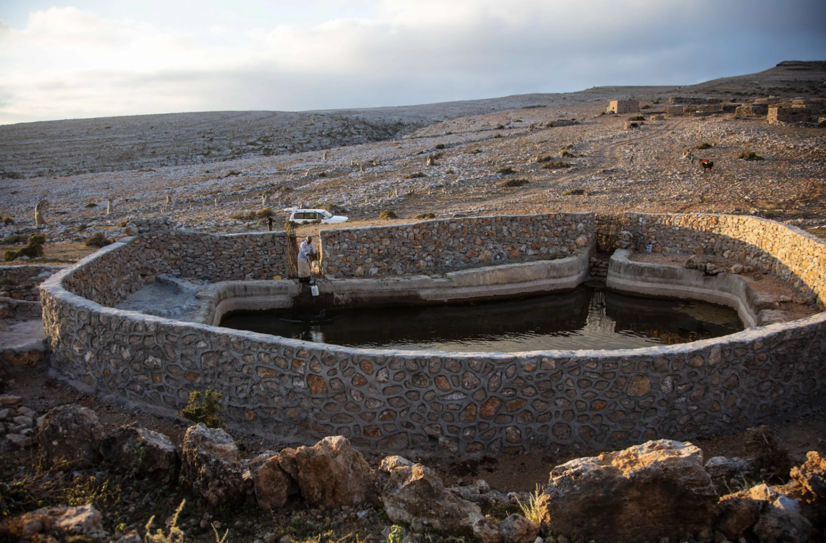 Image d'un mur de soutènement autour d'un réservoir d'eau de pluie au milieu d'un paysage désertique.