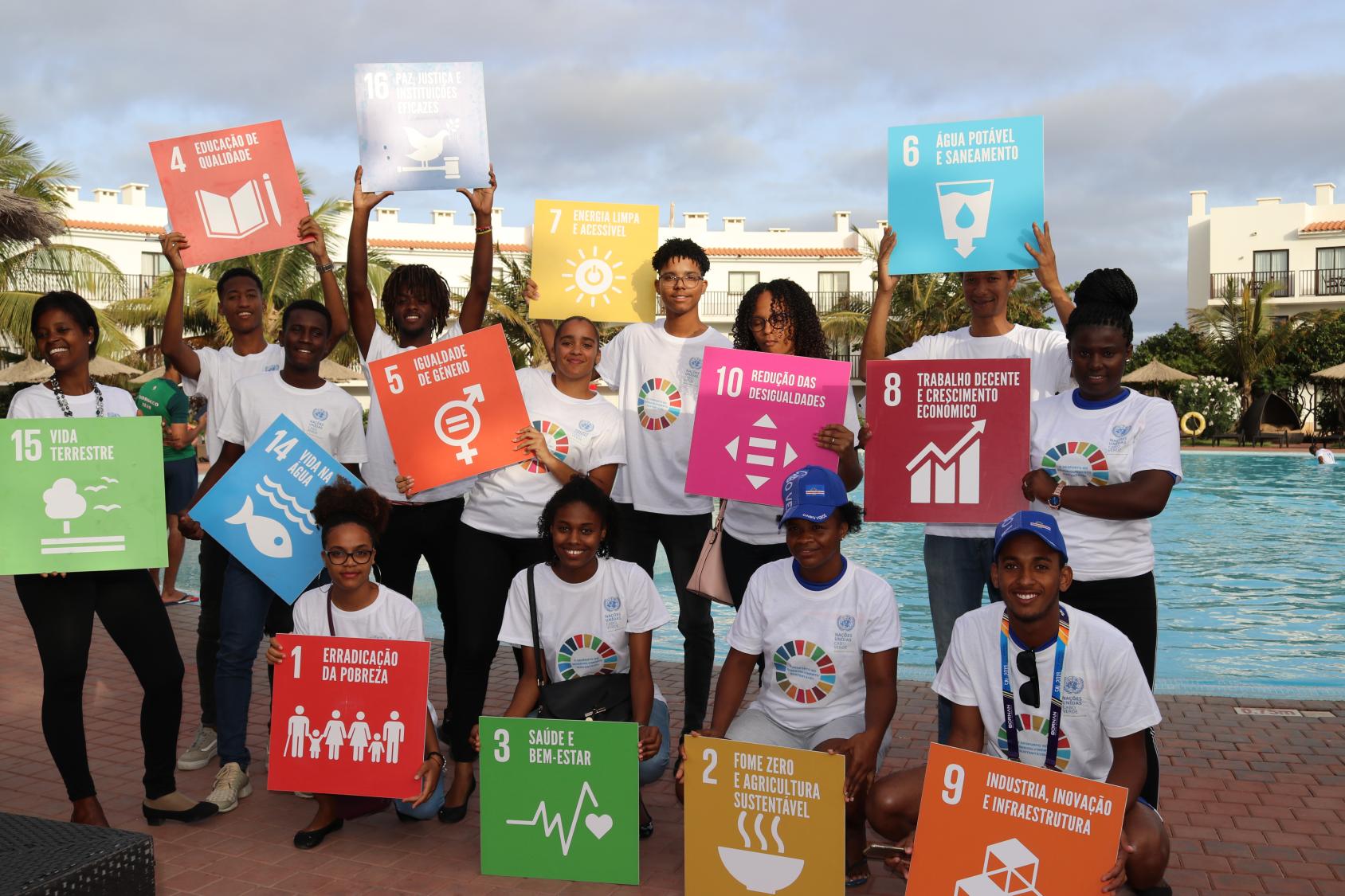 Young people smile happily as they pose with individual SDG signs each.
