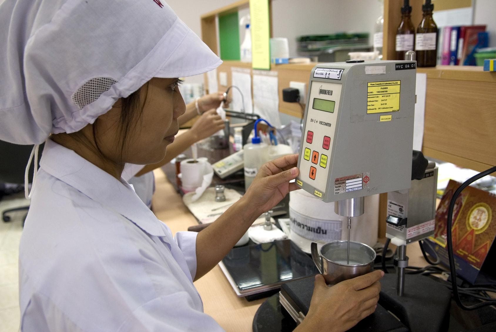 A woman in a Laboratory tests a product with a machine.