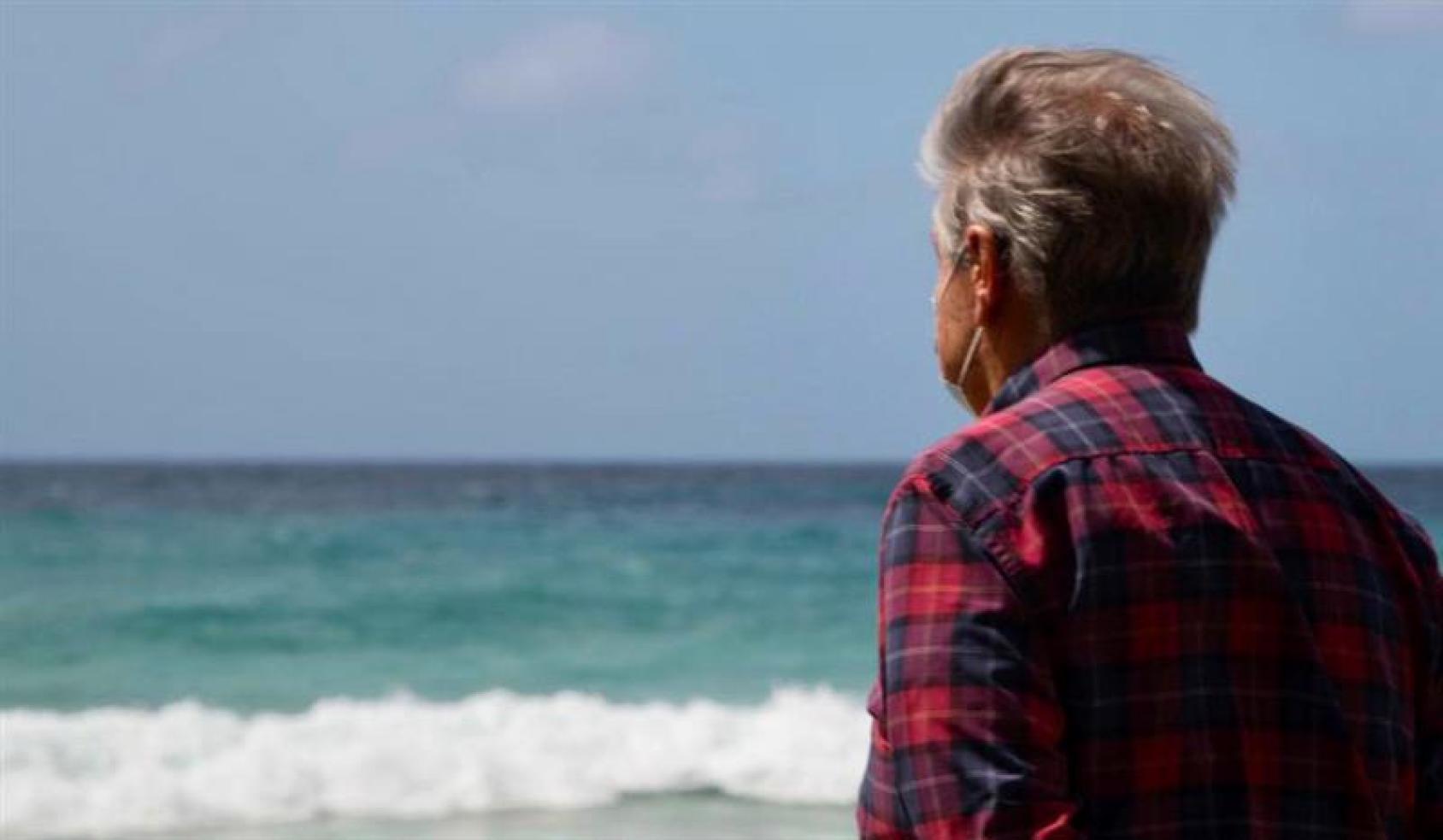 Le Secrétaire général des Nations Unies est photographié de dos en train de regarder l'océan depuis une plage.