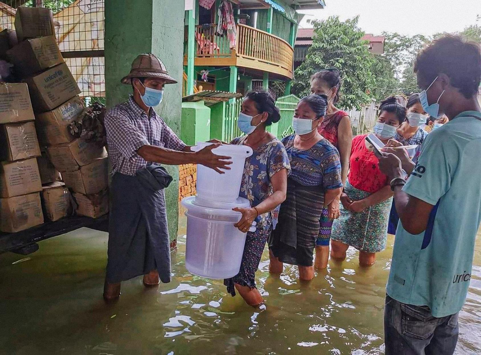 People receiving goods from a truck with water up to their knees. 