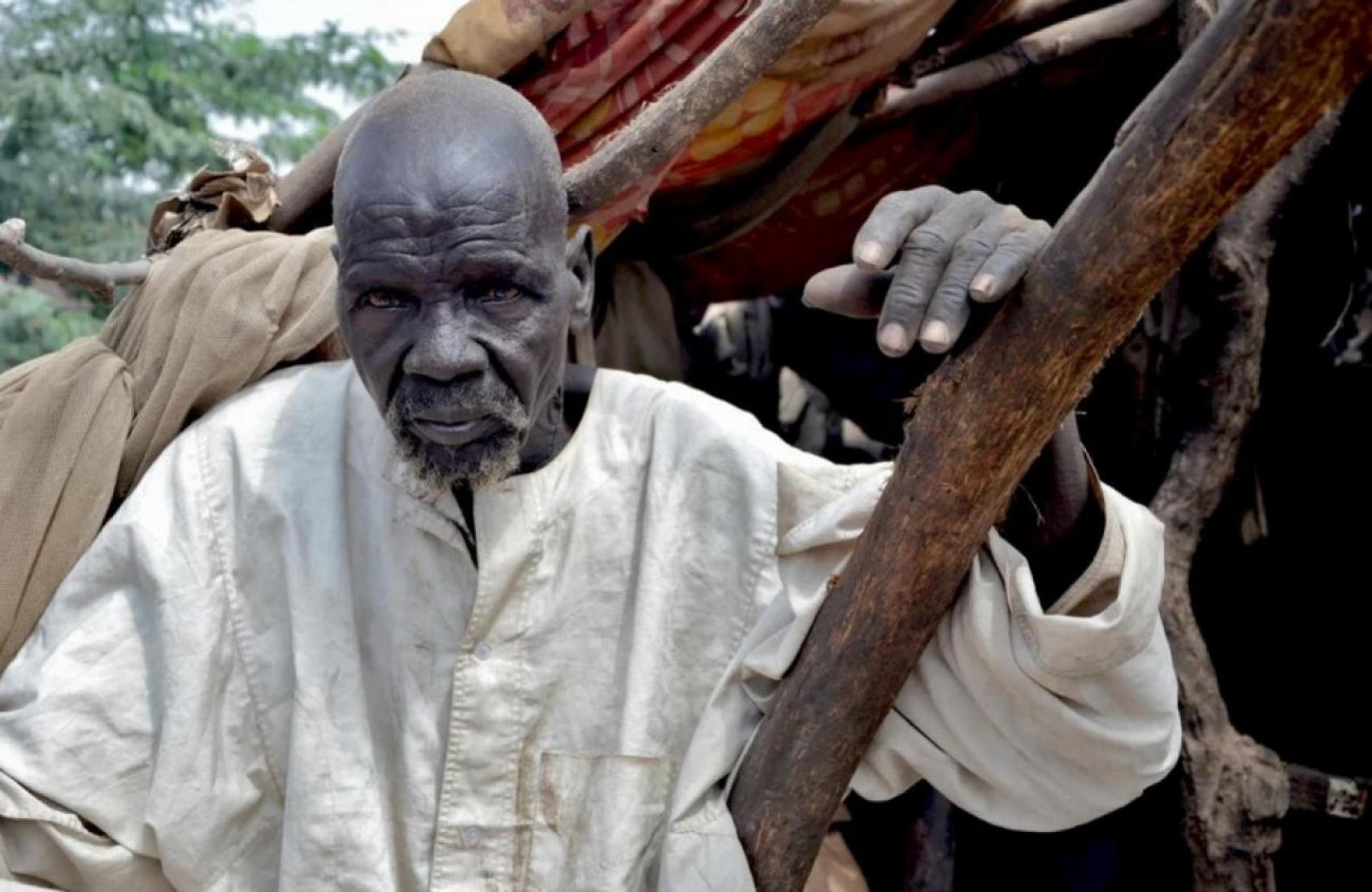 Au Soudan, Bak, un réfugié âgé, est assis près de son abri, qui a été endommagé par des inondations. 