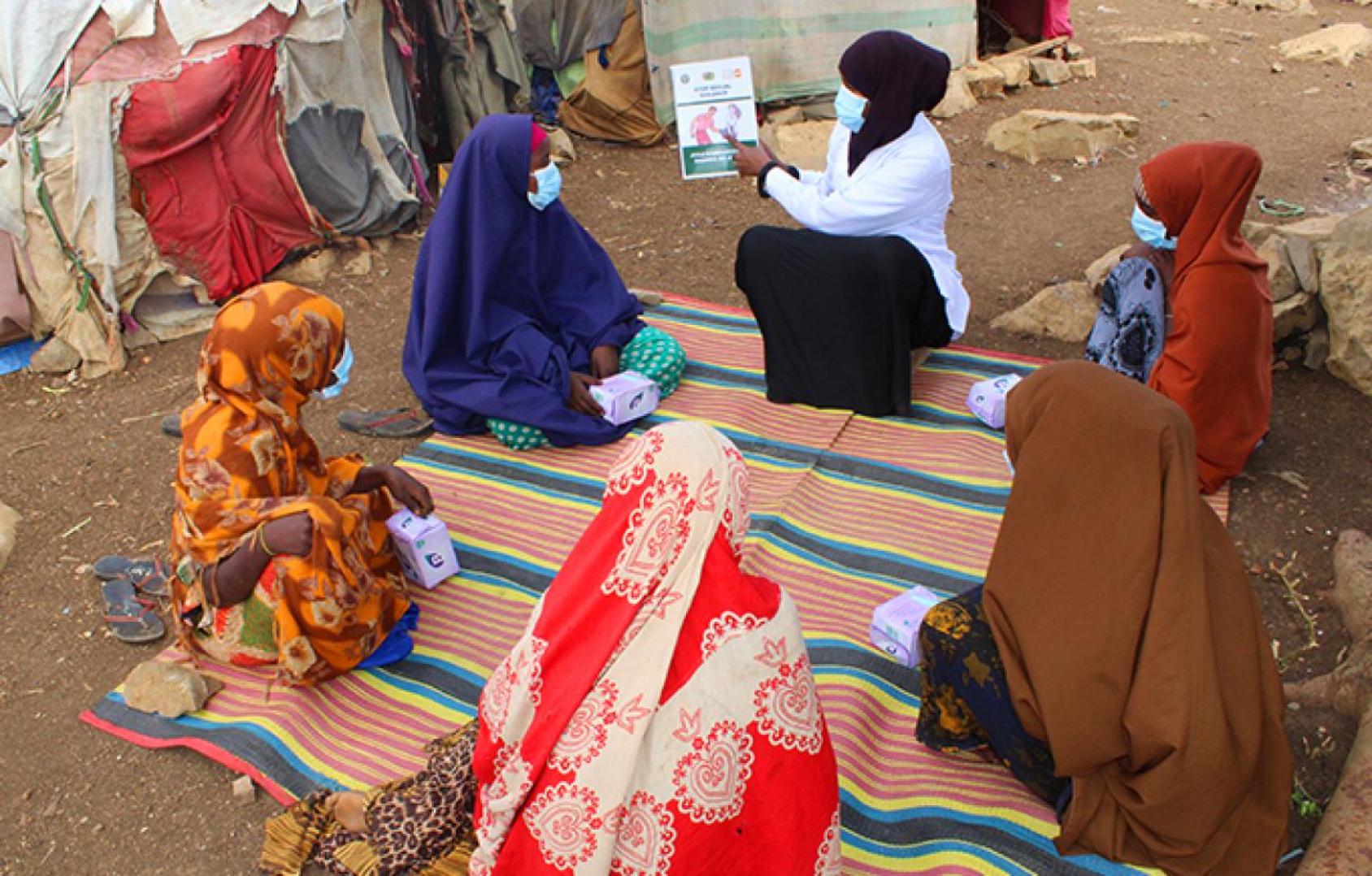 Un grupo de mujeres se sientan en círculo mirando un folleto informativo.