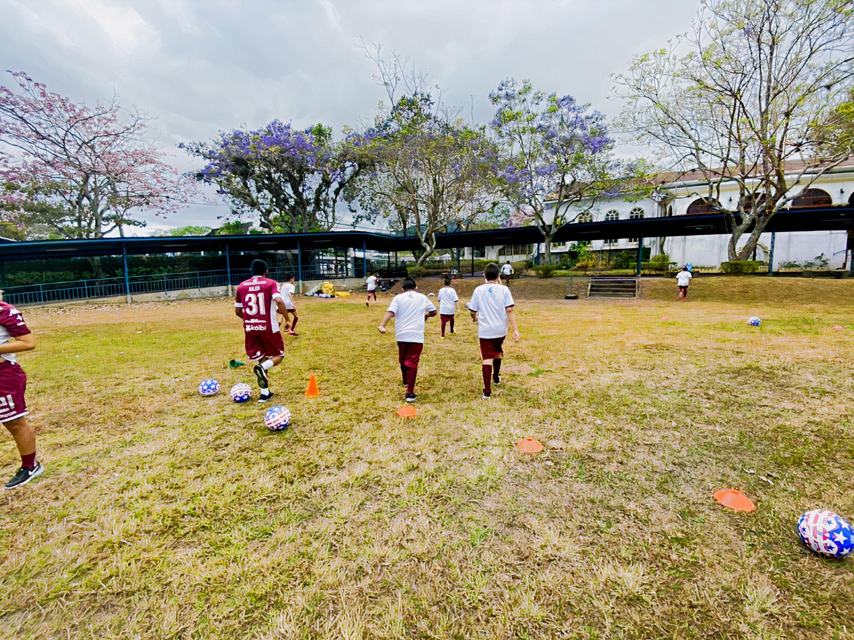 Children in white and purple uniforms practice soccer.