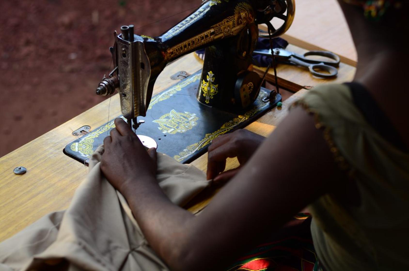 Imagen de las manos de una chica mientras trabaja en una máquina de coser.