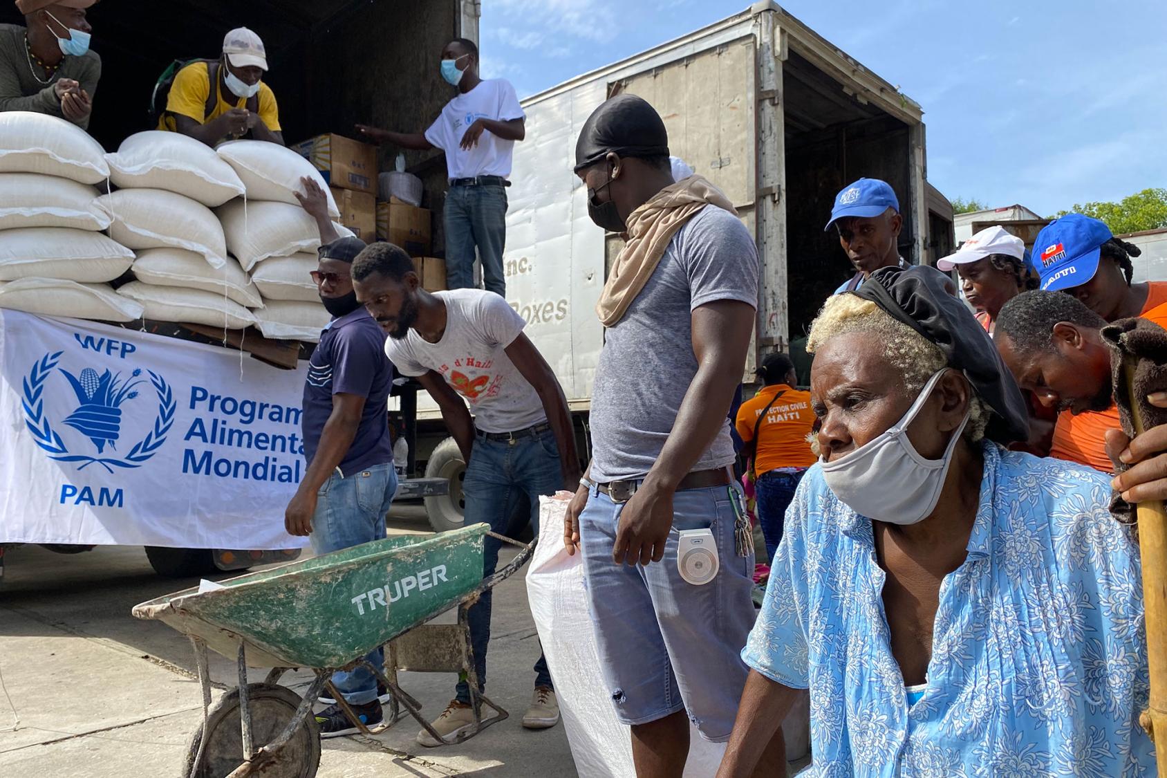 En Haïti, des personnes viennent décharger des camions pour récupérer l’aide alimentaire d'urgence qui a été livrée au pays par le Programme alimentaire mondial immédiatement après le tremblement de terre survenu en août 2021. 