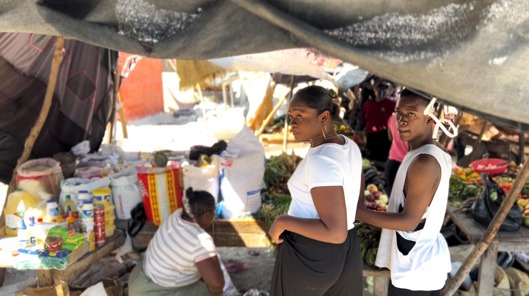 Une femme en Haïti, debout dans un marché de rue.