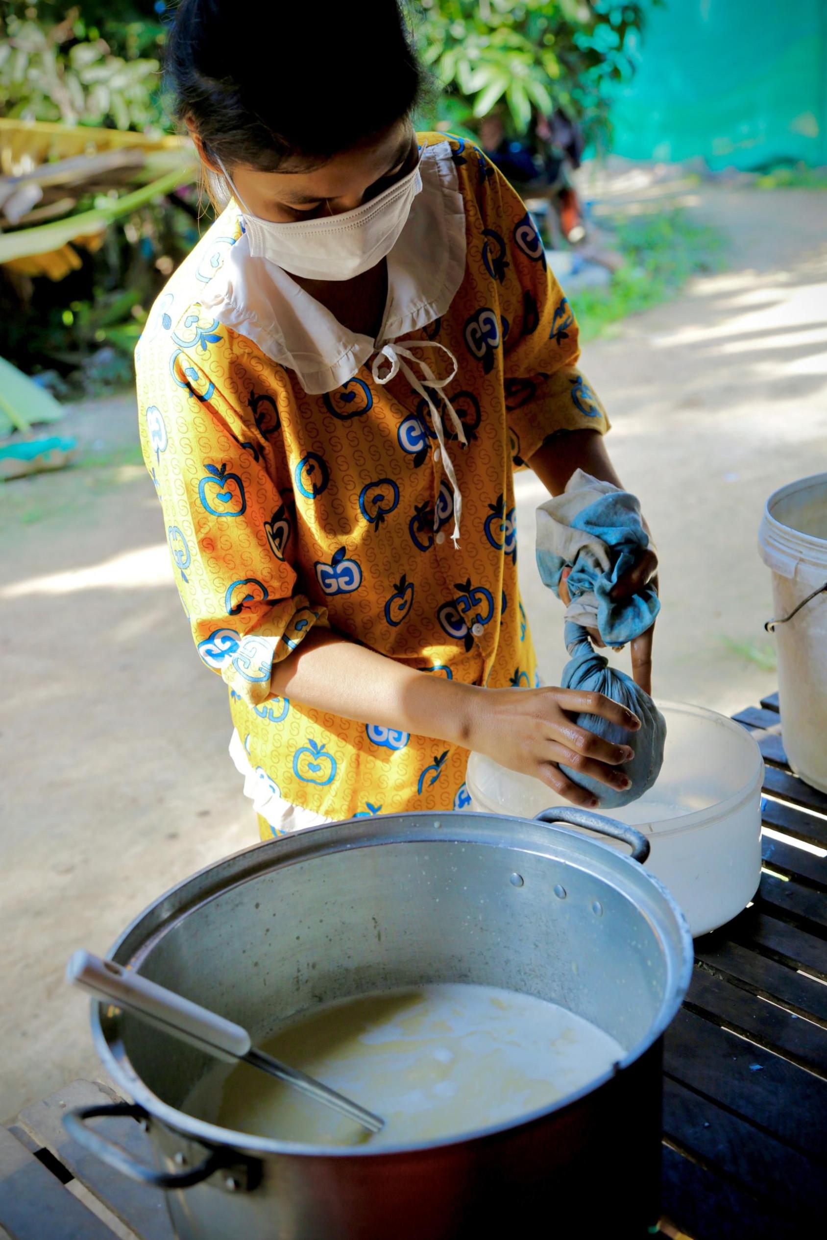 Una mujer exprime granos de soja cocidos en una toalla para hacer leche de soja.