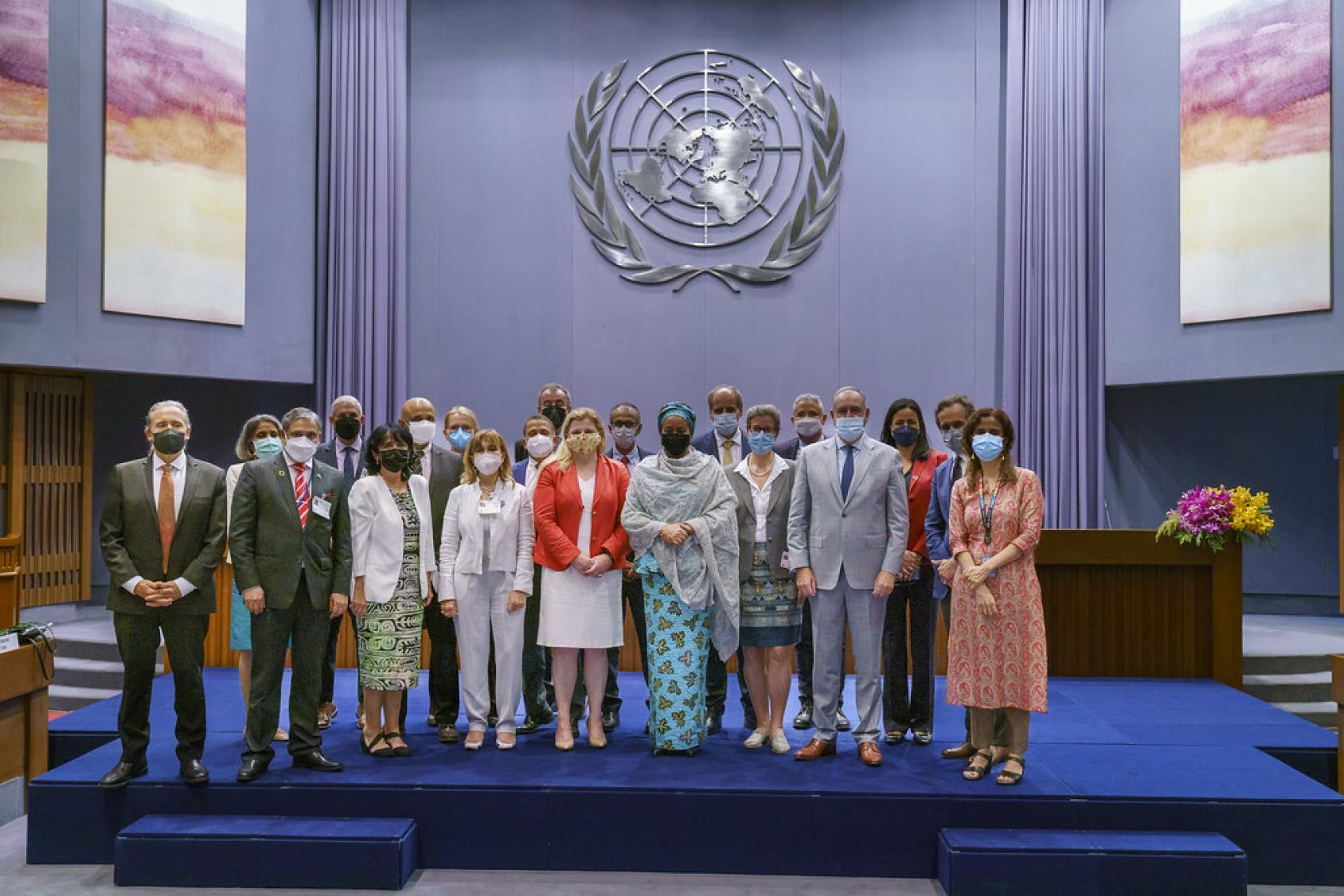 Un groupe de hauts représentants de l'ONU se tiennent debout, côte à côte, sur un estrade, et posent pour une photo. 