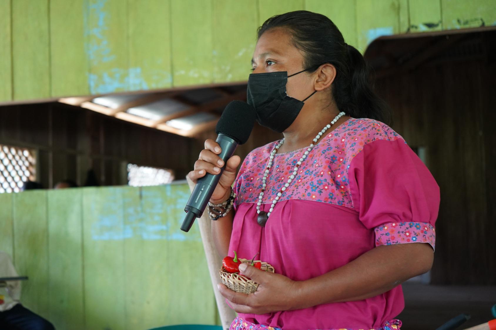 Una mujer indígena Naso Tjër Di con una máscara facial y hablando por el micrófono.
