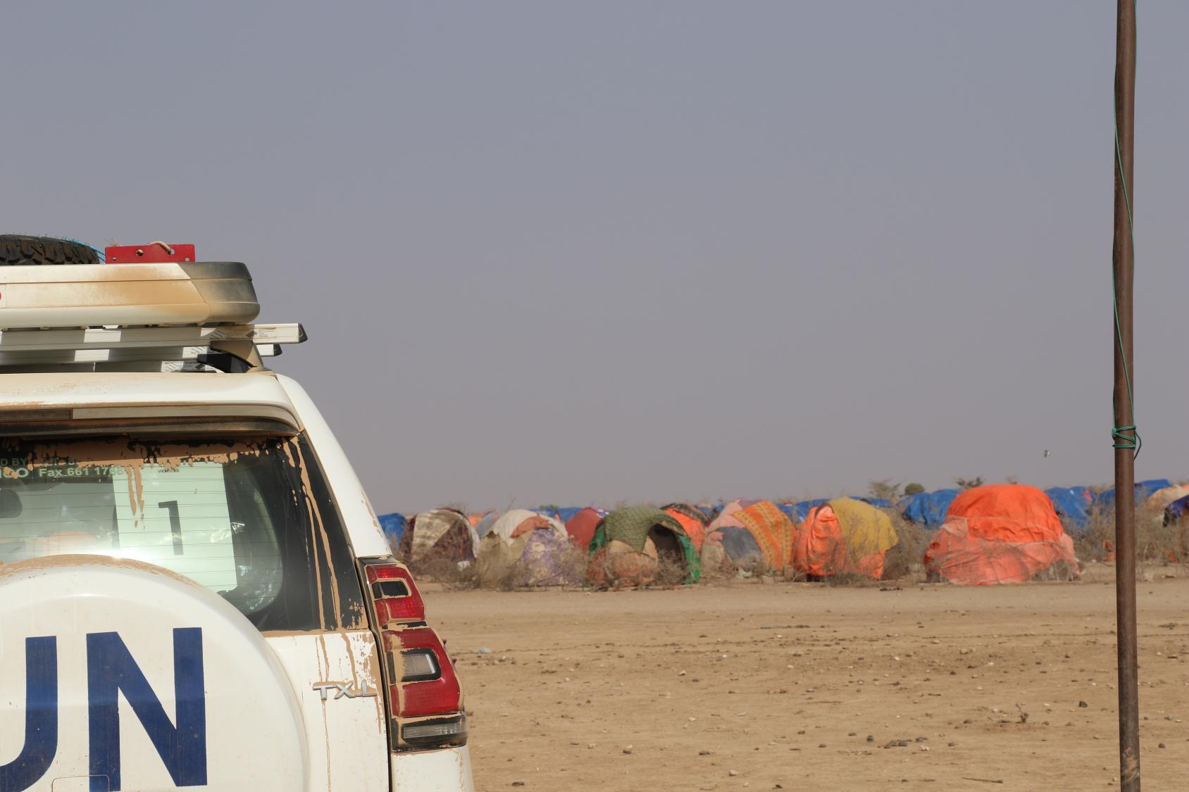 一辆印有联合国标志的吉普车驶过沙漠。