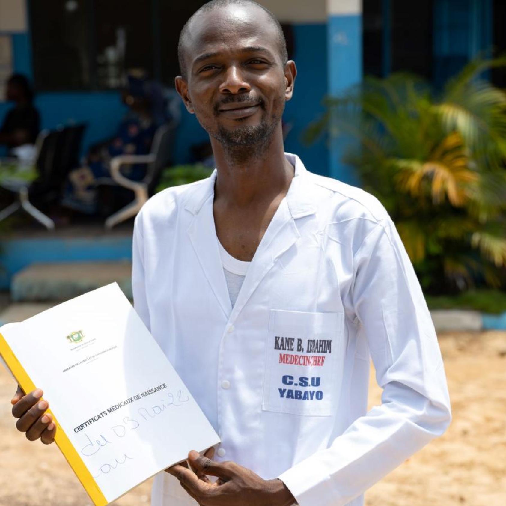 Un médico mostrando un certificado de nacimiento, en el exterior del centro sanitario de Yabayo, en Soubré (Côte d'Ivoire).