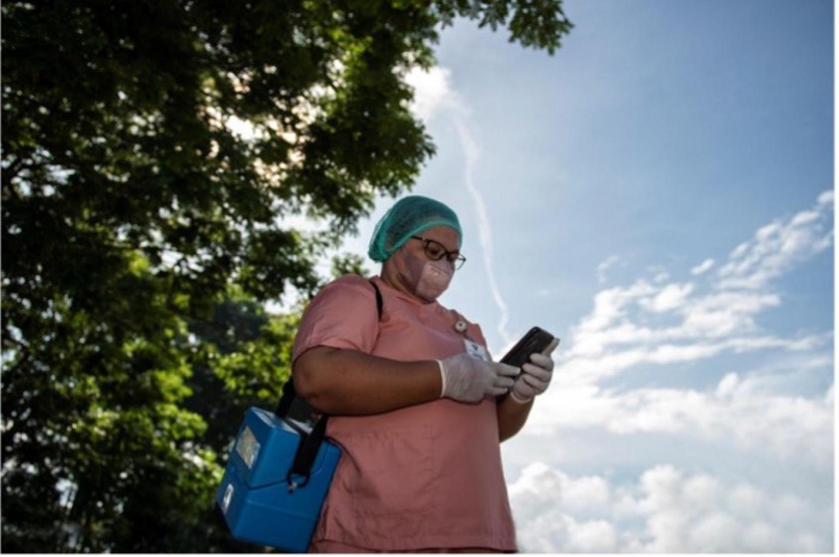 En Indonésie, un membre féminin du personnel de santé utilise l'application SMILE pour consigner les vaccins qu'elle a administrés sur le terrain.