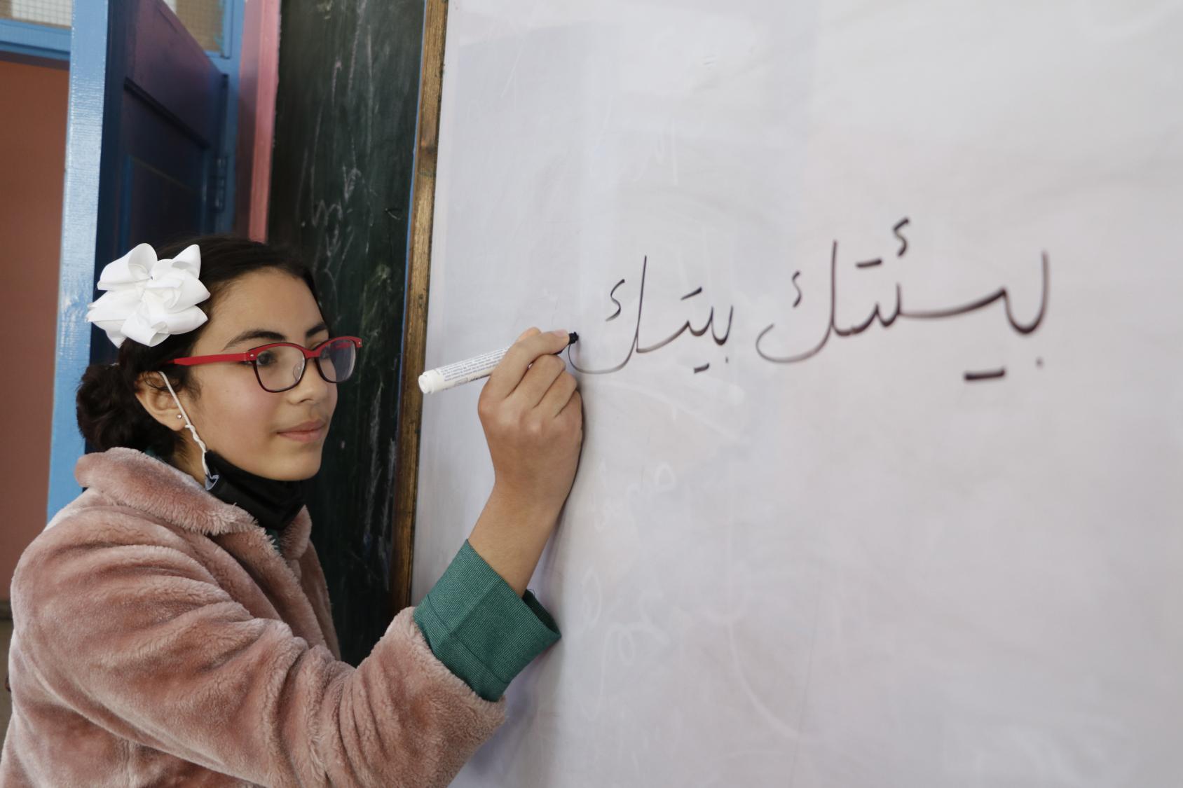 Una mujer joven escribiendo en una pizarra: "tu entorno es tu casa".