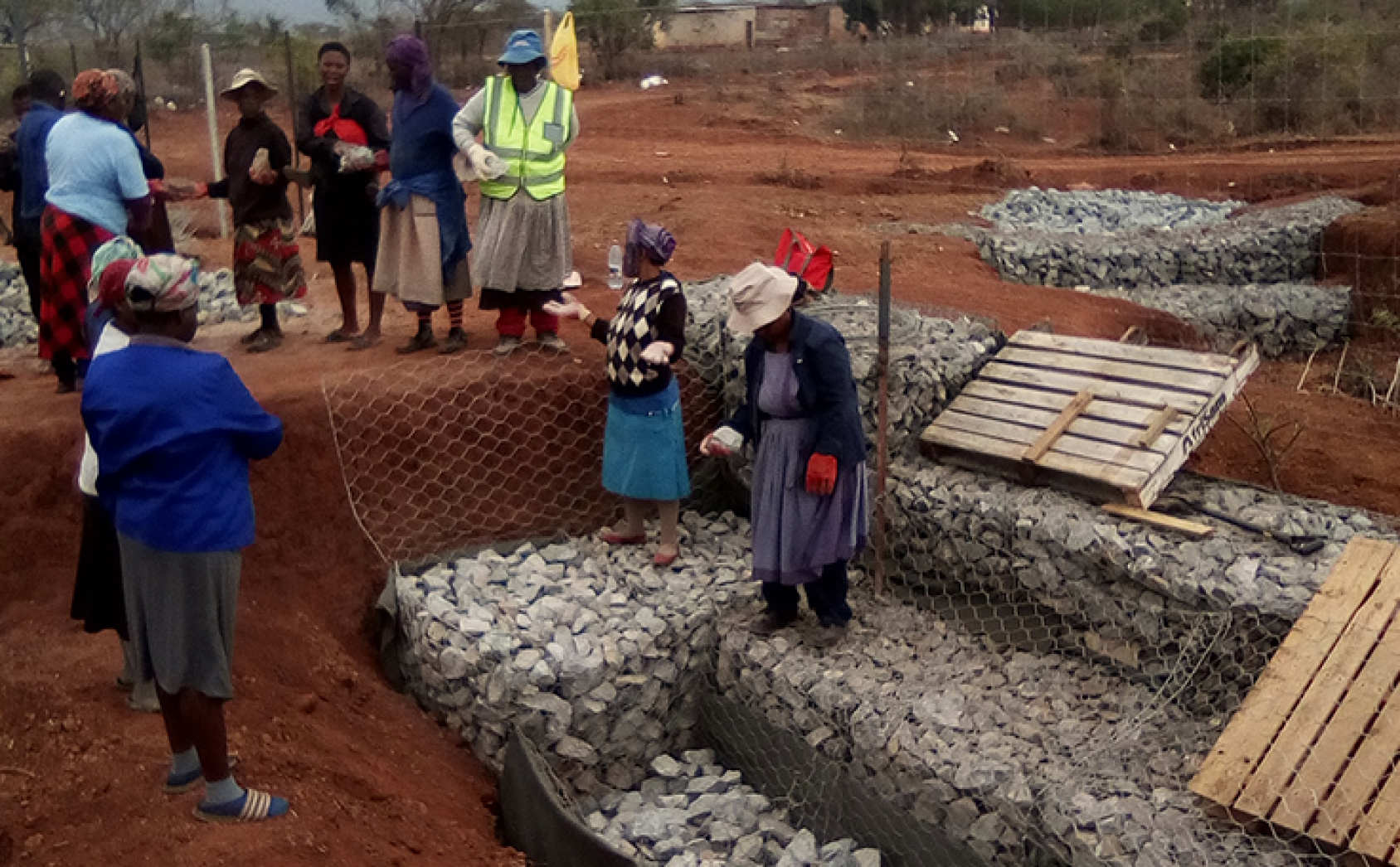 Des habitants de Nceka, en Eswatini, remplissent des cages métalliques de pierres pour boucher les ravines causées par l'érosion du sol combinée à de fortes pluies.