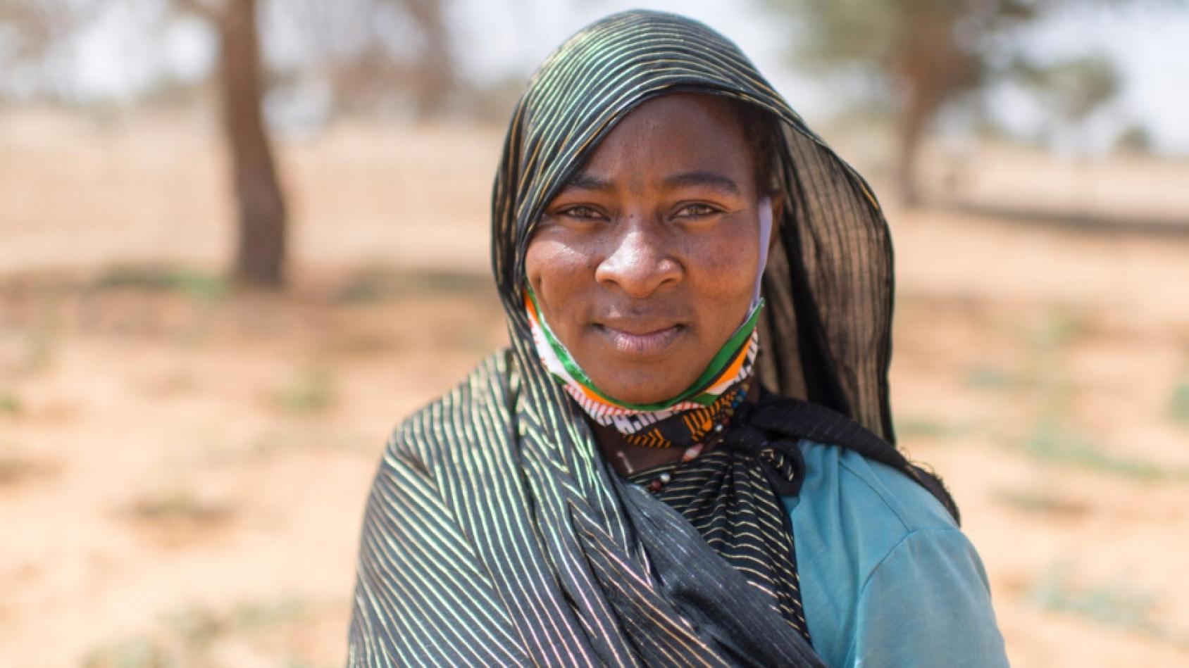 Primer plano de una mujer maliense con un pañuelo gris en la cabeza y los hombros.