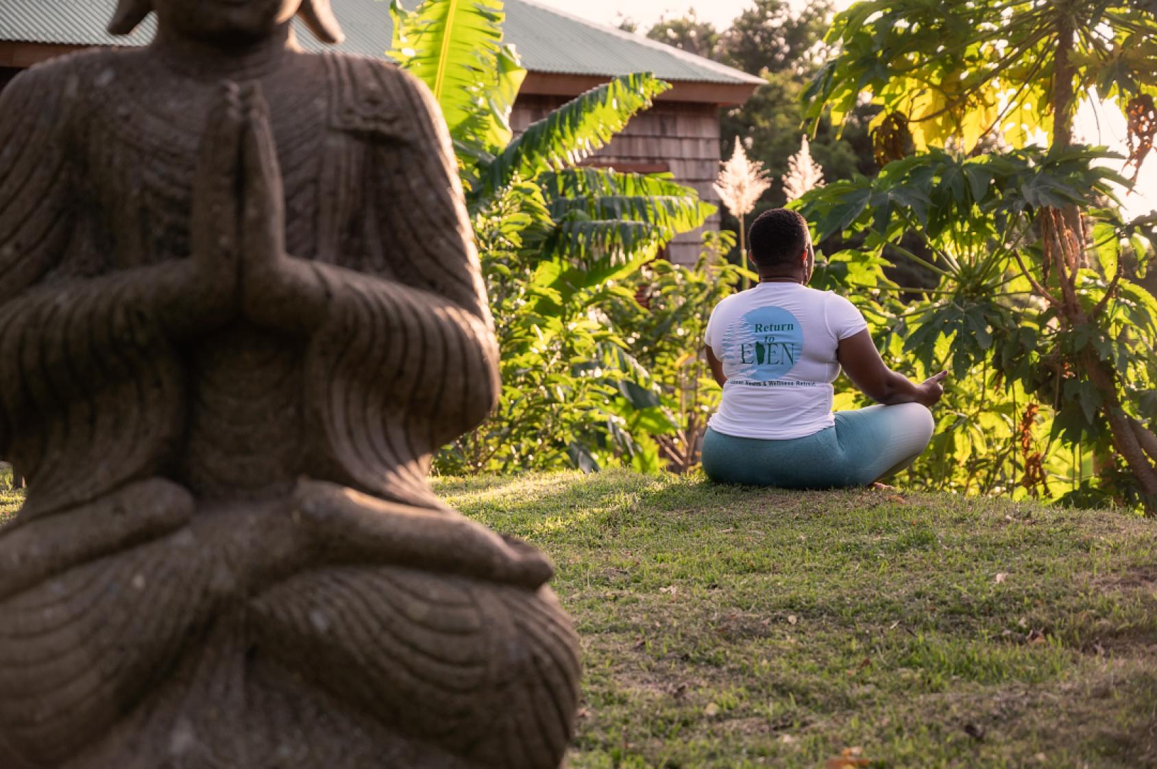 A person meditating in a green area.