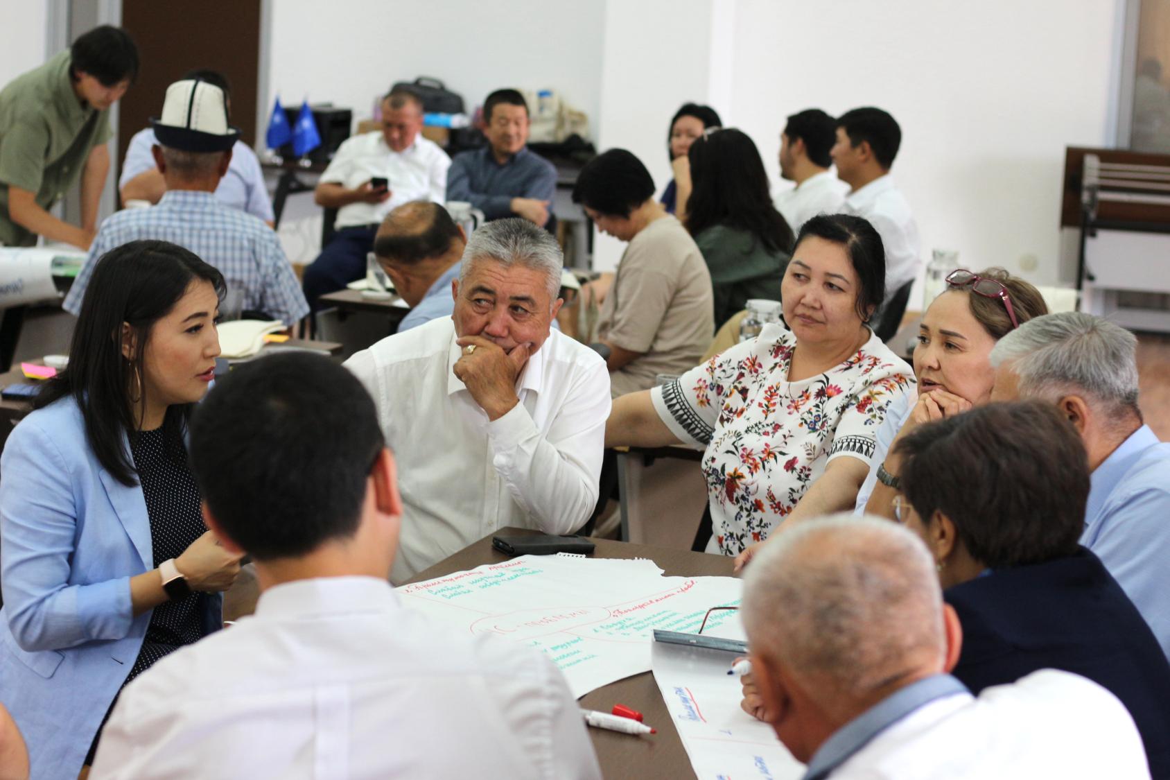 En République kirghize, les participants à une formation discutent autour d'une table des menaces liées au réchauffement climatique et des risques associés à la raréfaction des ressources en eau. 