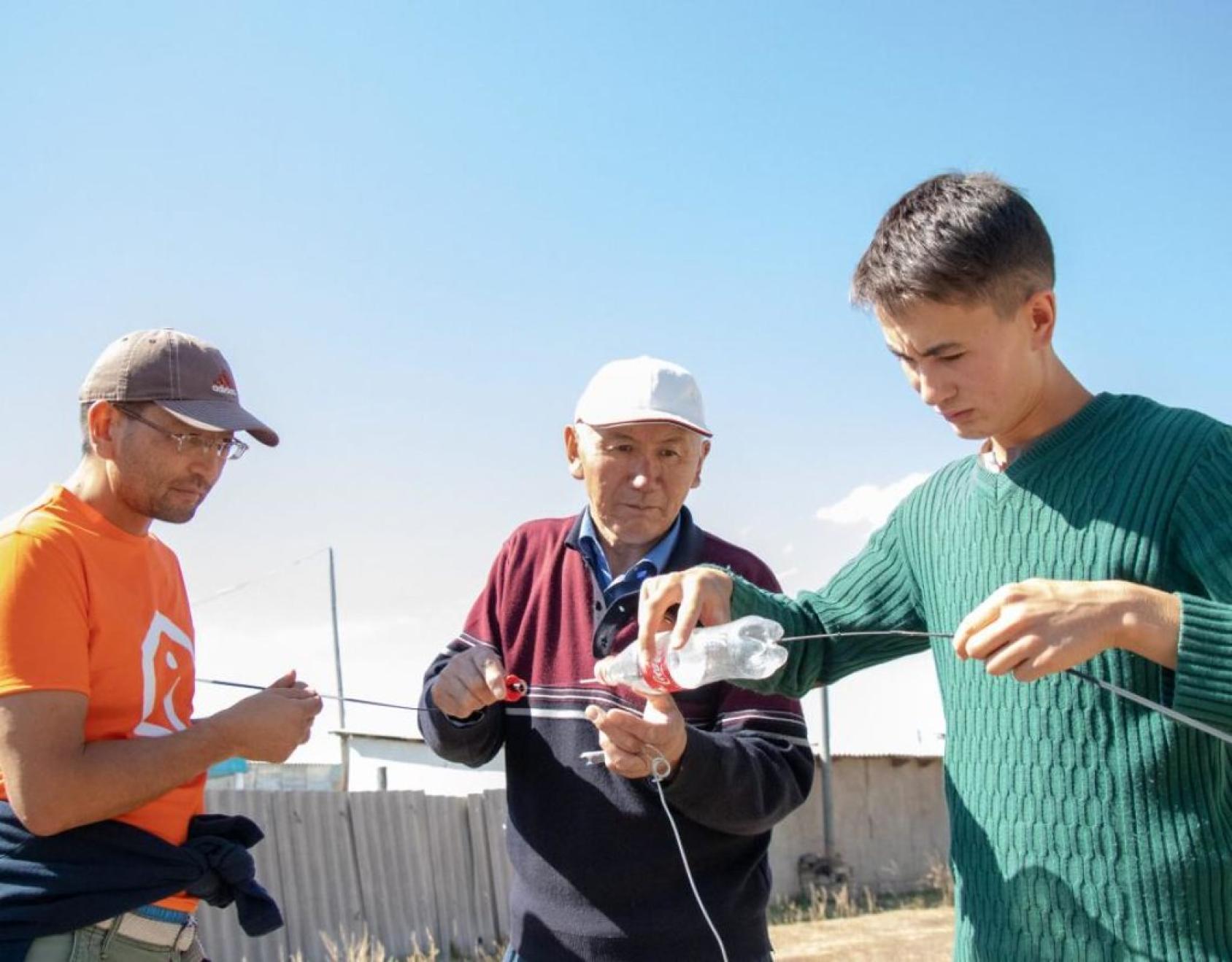 Au Kirghizistan, trois hommes recouvrent des câbles de connexion à Internet pour les protéger des intempéries.