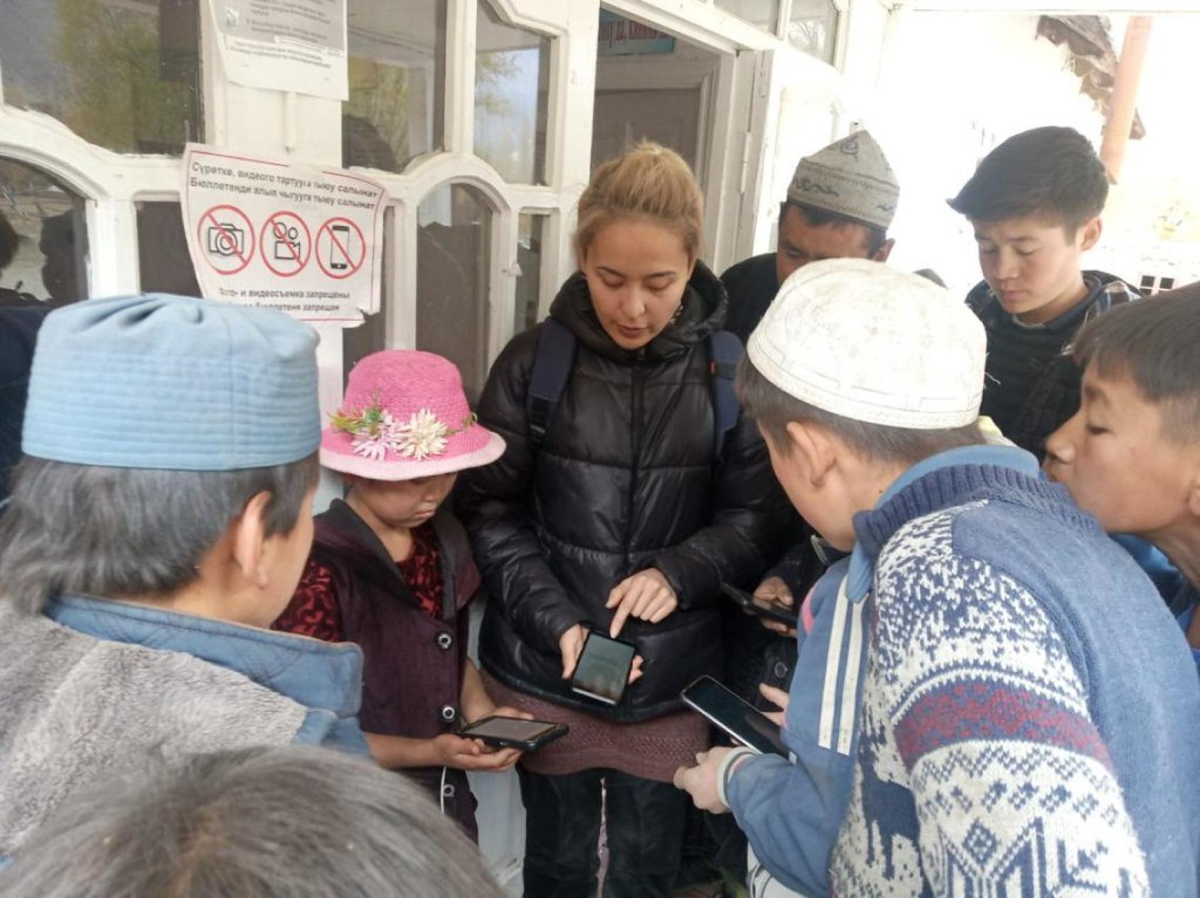 Au Kirghizistan, une femme explique à un groupe d'enfants comment utiliser une application pour smartphone. 