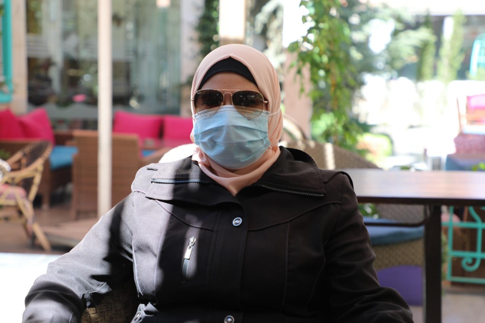 Женщина в хиджабе, темных очках и медицинской маске.