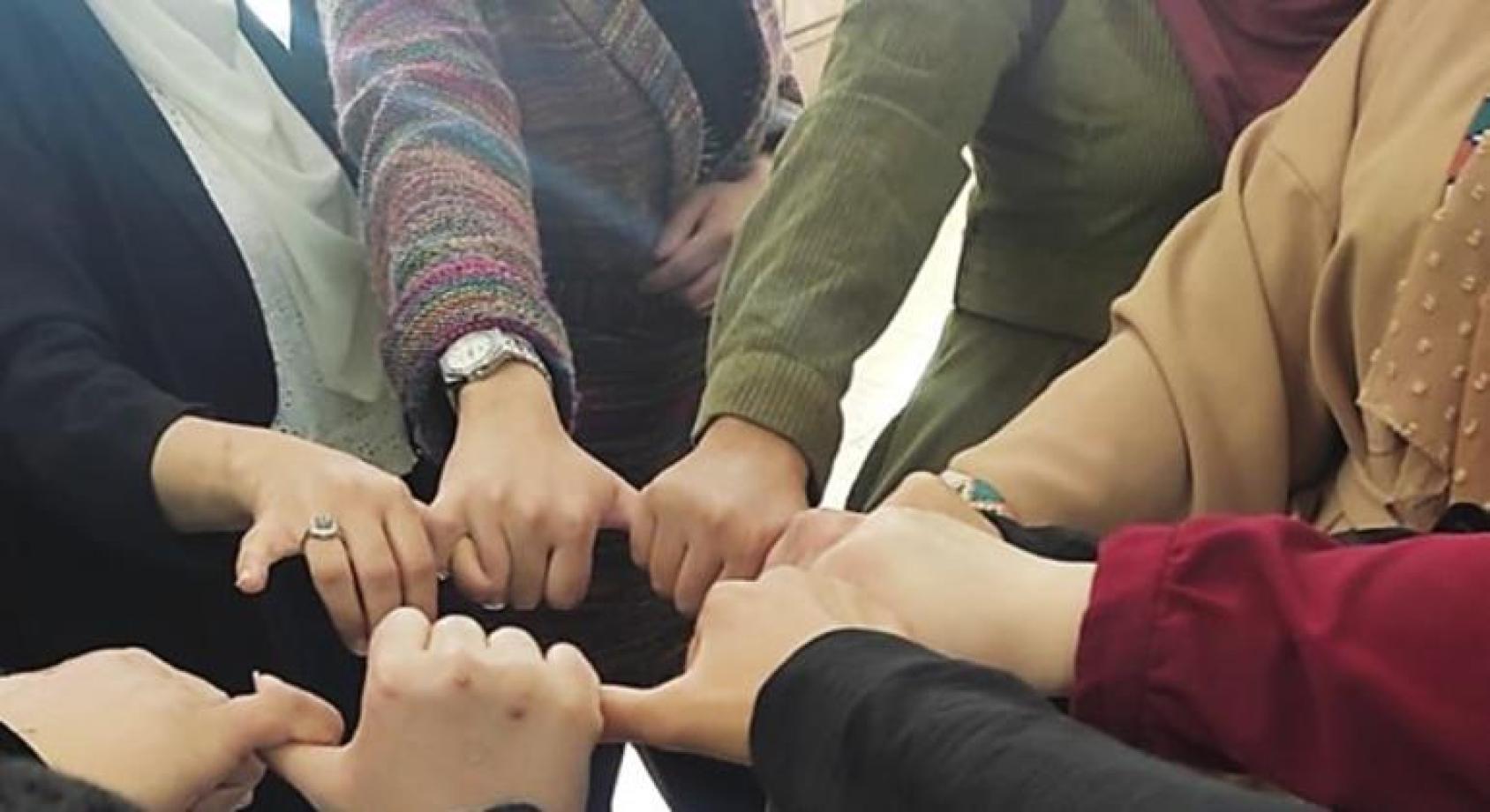 Gros plan sur des mains de femmes qui se joignent les unes aux autres en signe de solidarité.