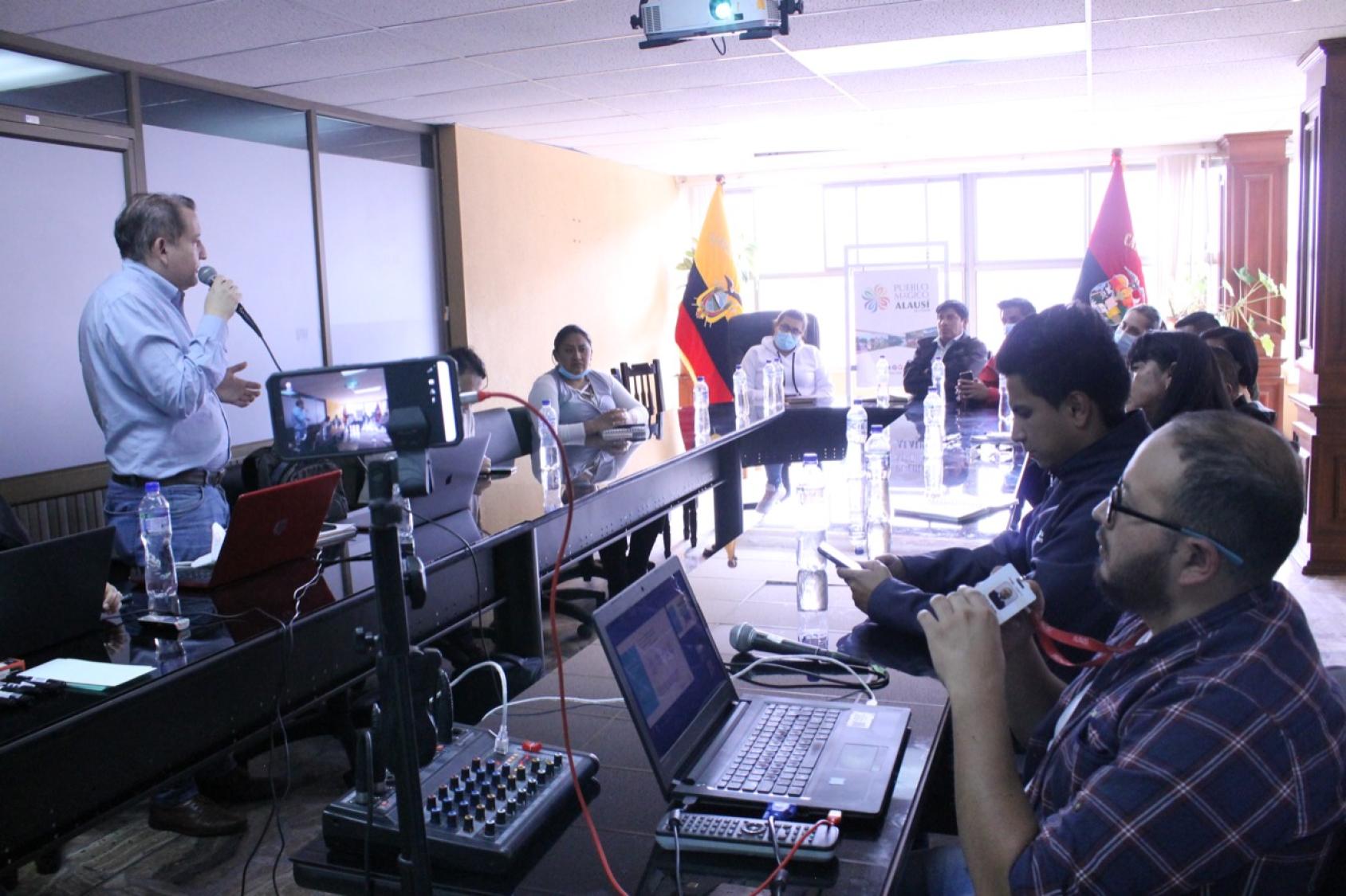 Un grupo de consultores reunidos en una sala con la bandera de Ecuador en el fondo.