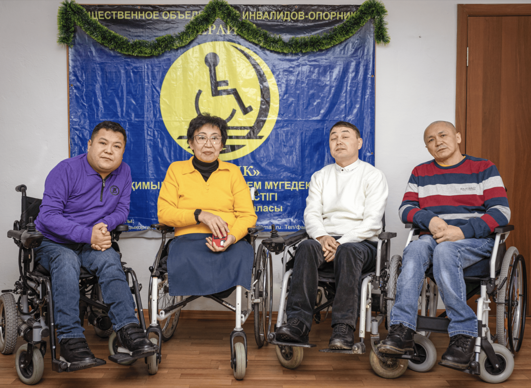 Four persons on wheelchairs against a blue background