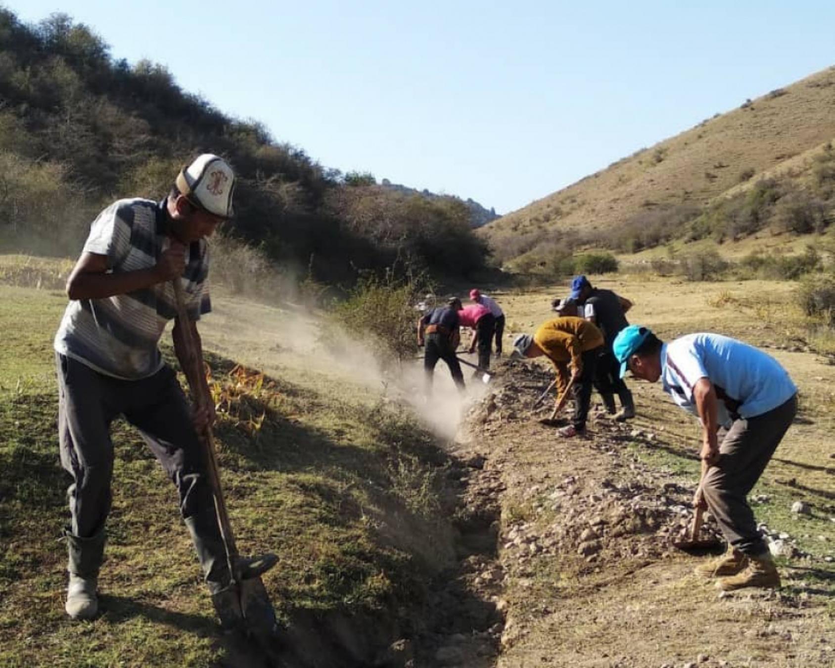 A group of people work with digging tools in the Kygyz mountains