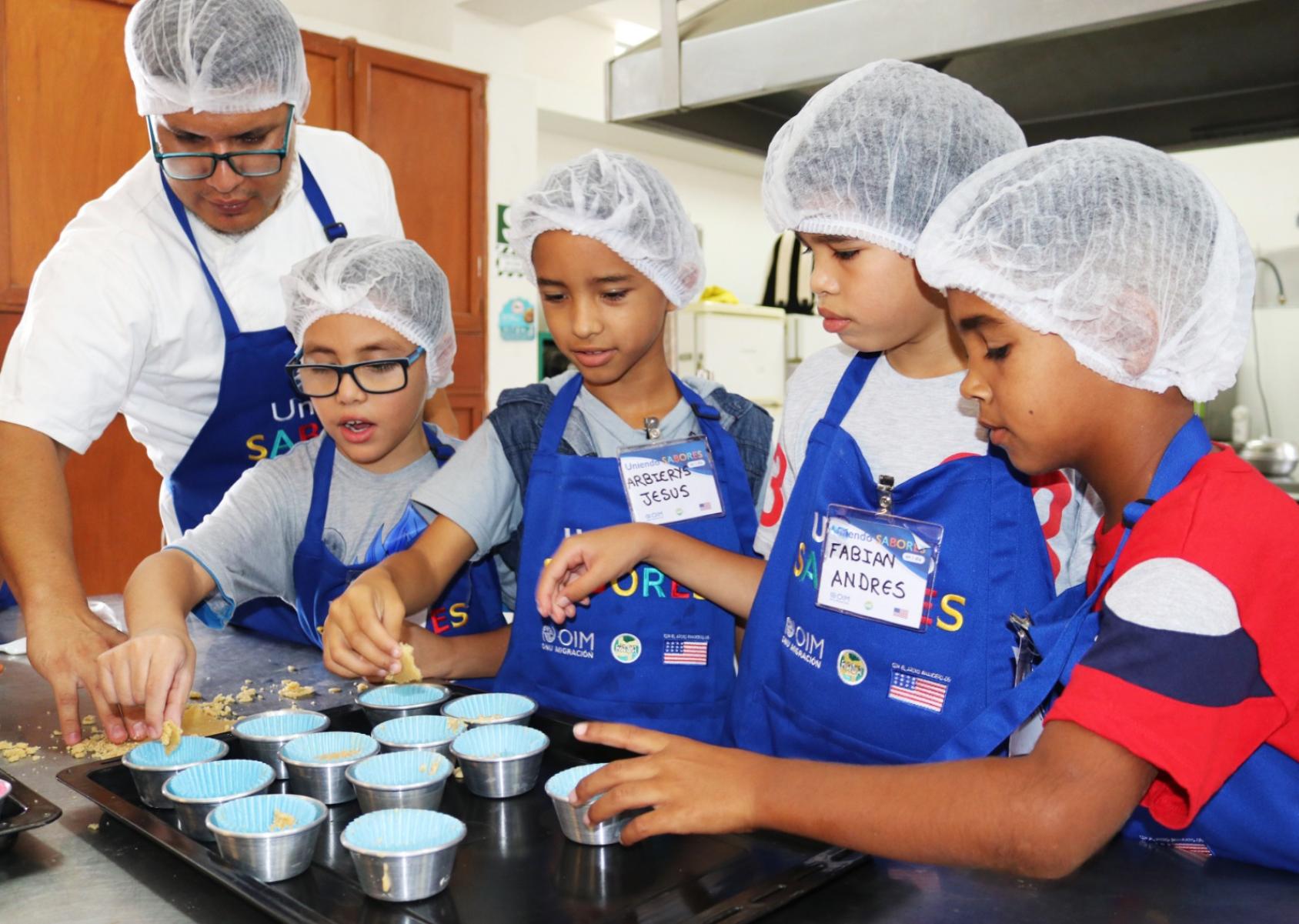 Four children in chefs caps bake together