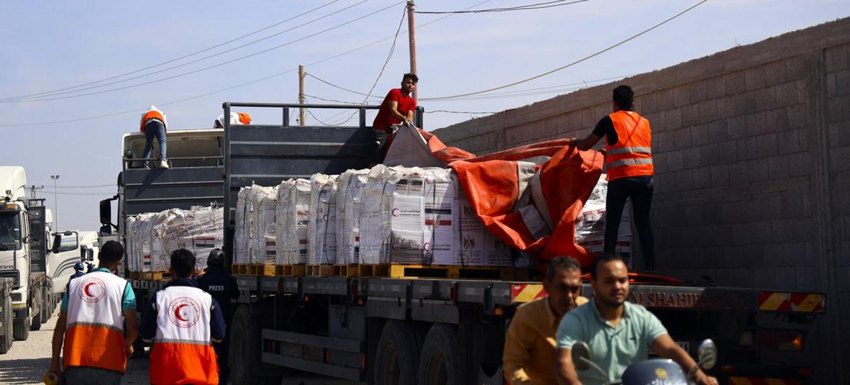 A giant truck carrying aid materials gets unloaded by workers