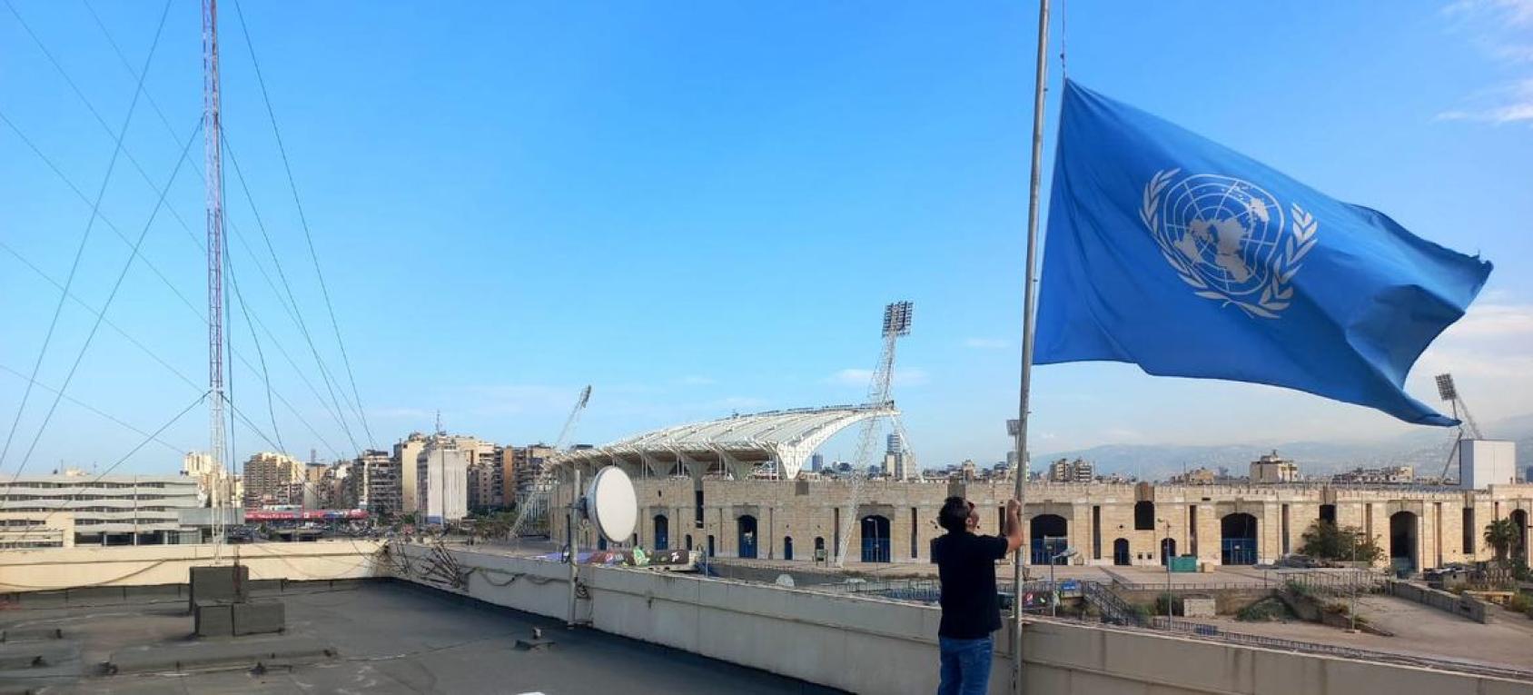 A man in Lebanon lowers the blue UN flag on the terrace of a building in Beirut