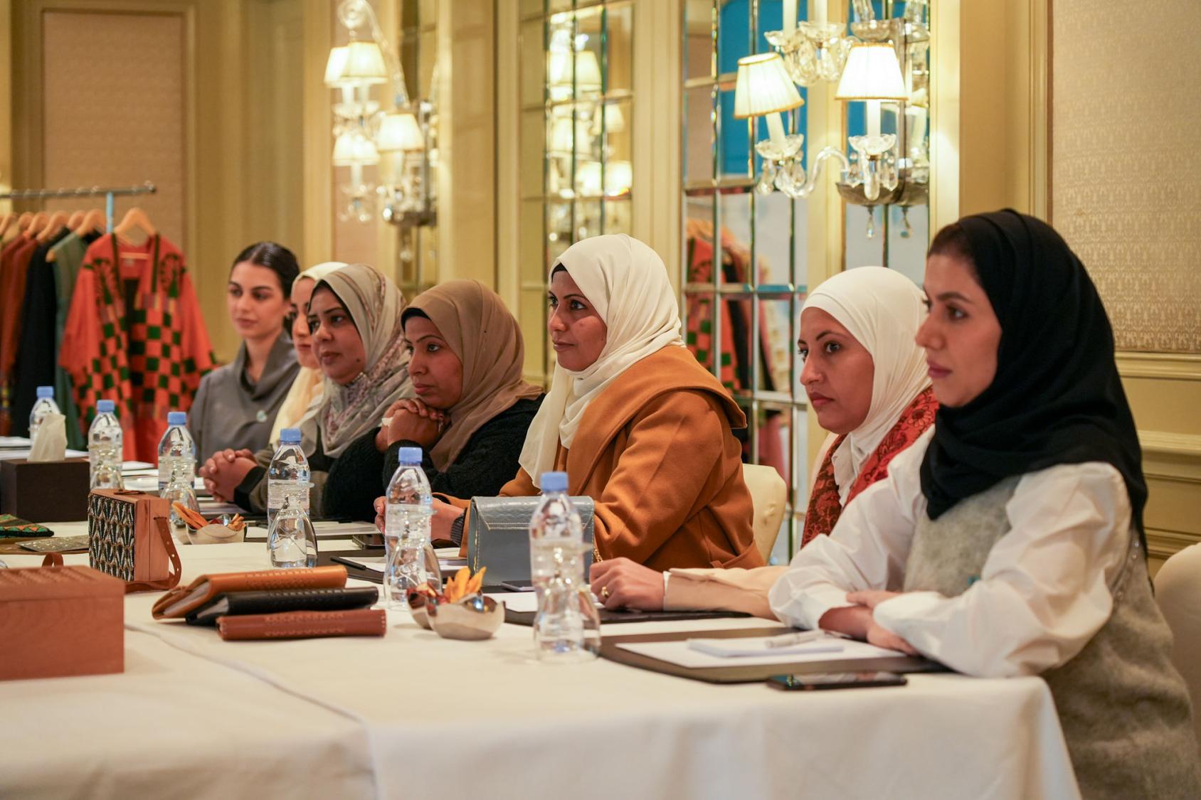 A group of Egyptian women sit at a table with a white tablecloth, as if in a meeting