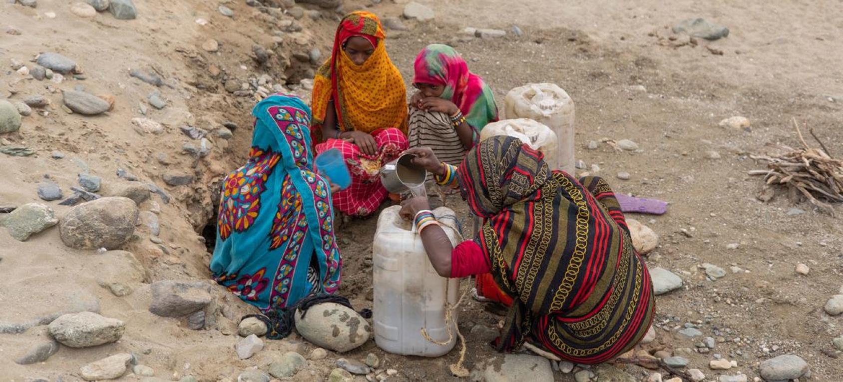 Four women are collecting water in a dry area 