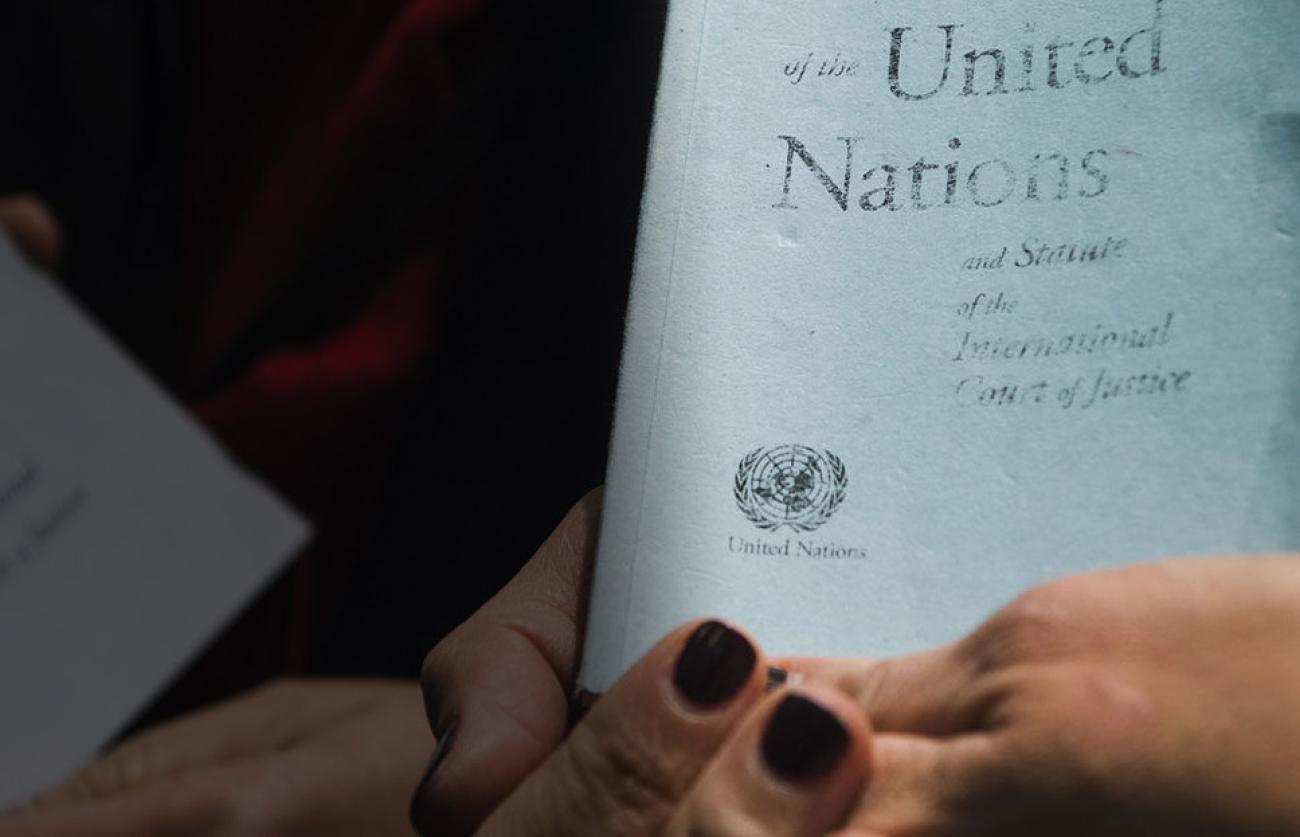 Gros plan sur les deux mains d'une femme tenant la Charte des Nations Unies en langue anglaise.