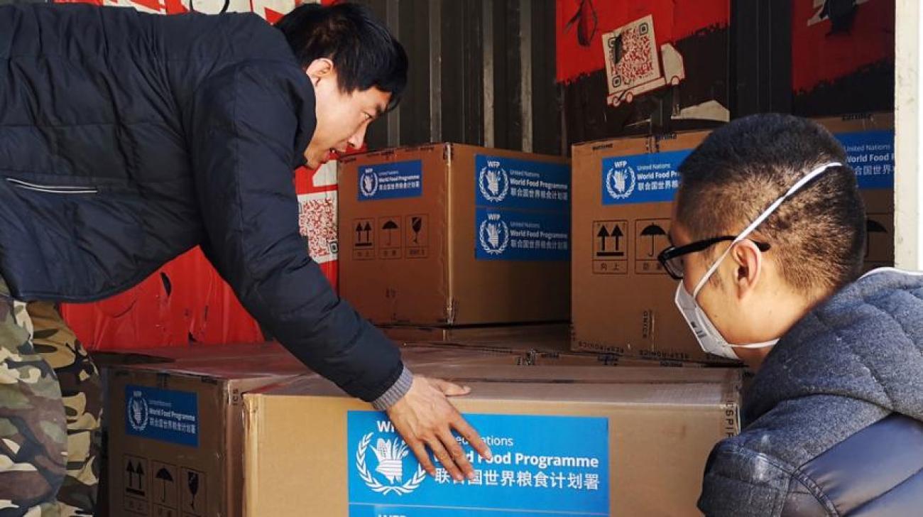Du matériel médical fourni par le Programme alimentaire mondial (PAM) arrive à Pékin. Deux hommes s'apprêtent à déballer le contenu des cartons livrés.