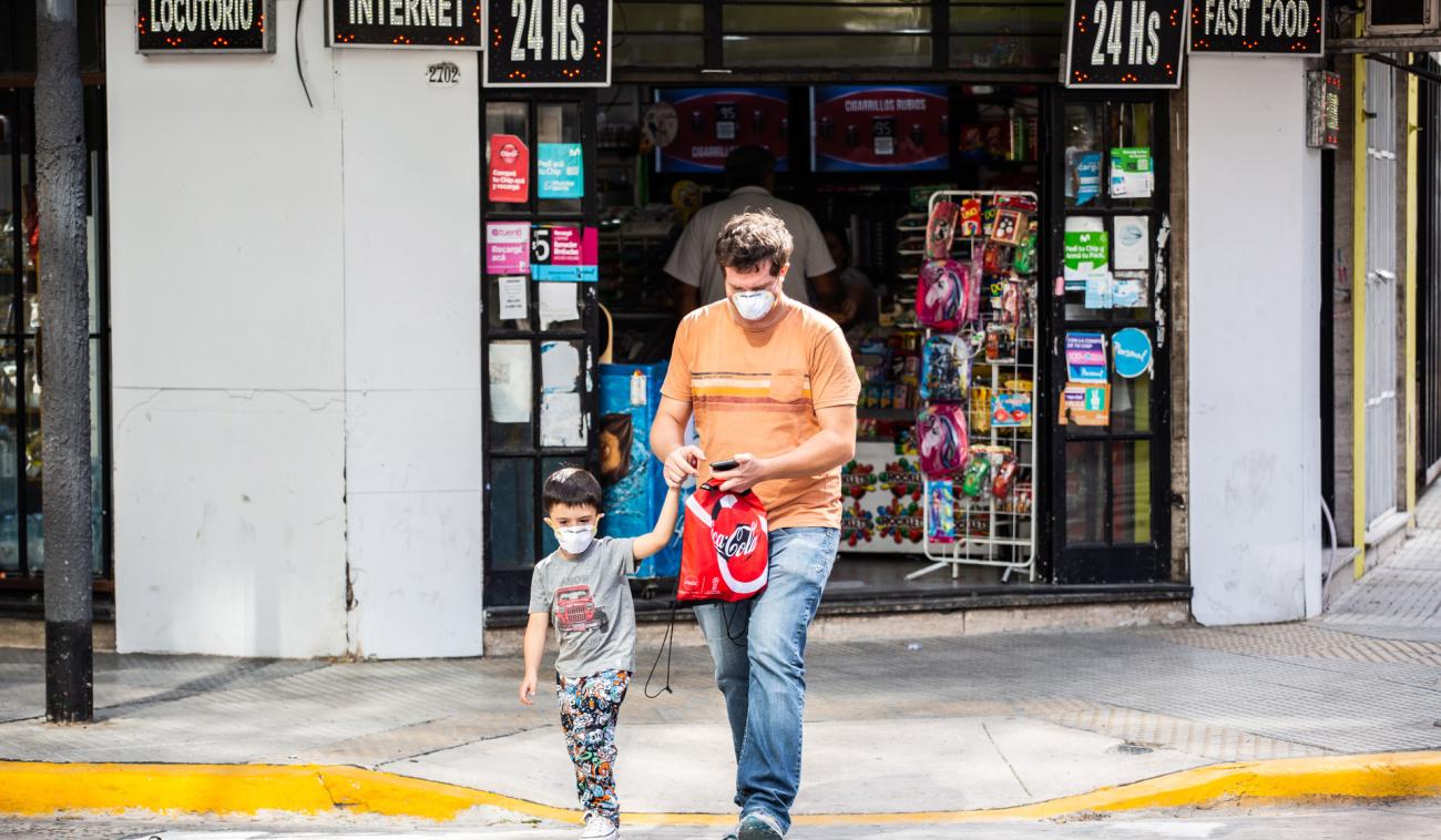 Padre e hijo con mascarilla protectora salen de una tienda.