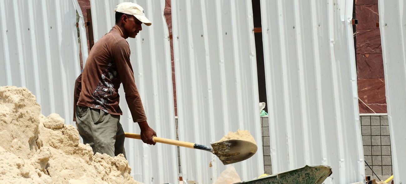 A labourer shoveling sand at a construction site.
