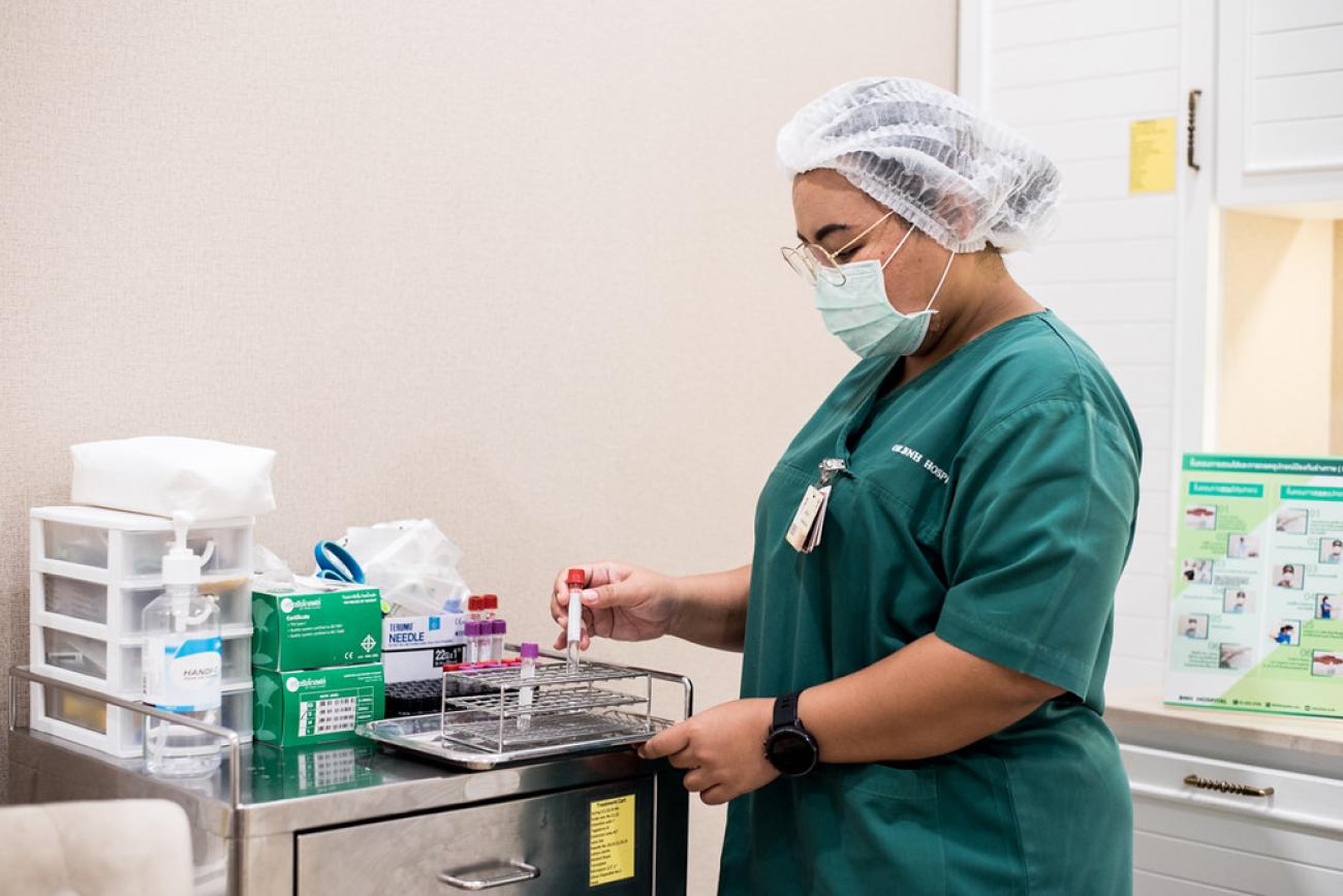ممرضة ترتدي معدات الوقاية الشخصية وهي تجهز مواد الفحص الطبي.