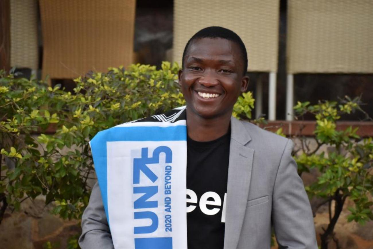 Photo montrant Majaha Mbuyisa portant une écharpe avec le logo UN75 et souriant à la caméra.